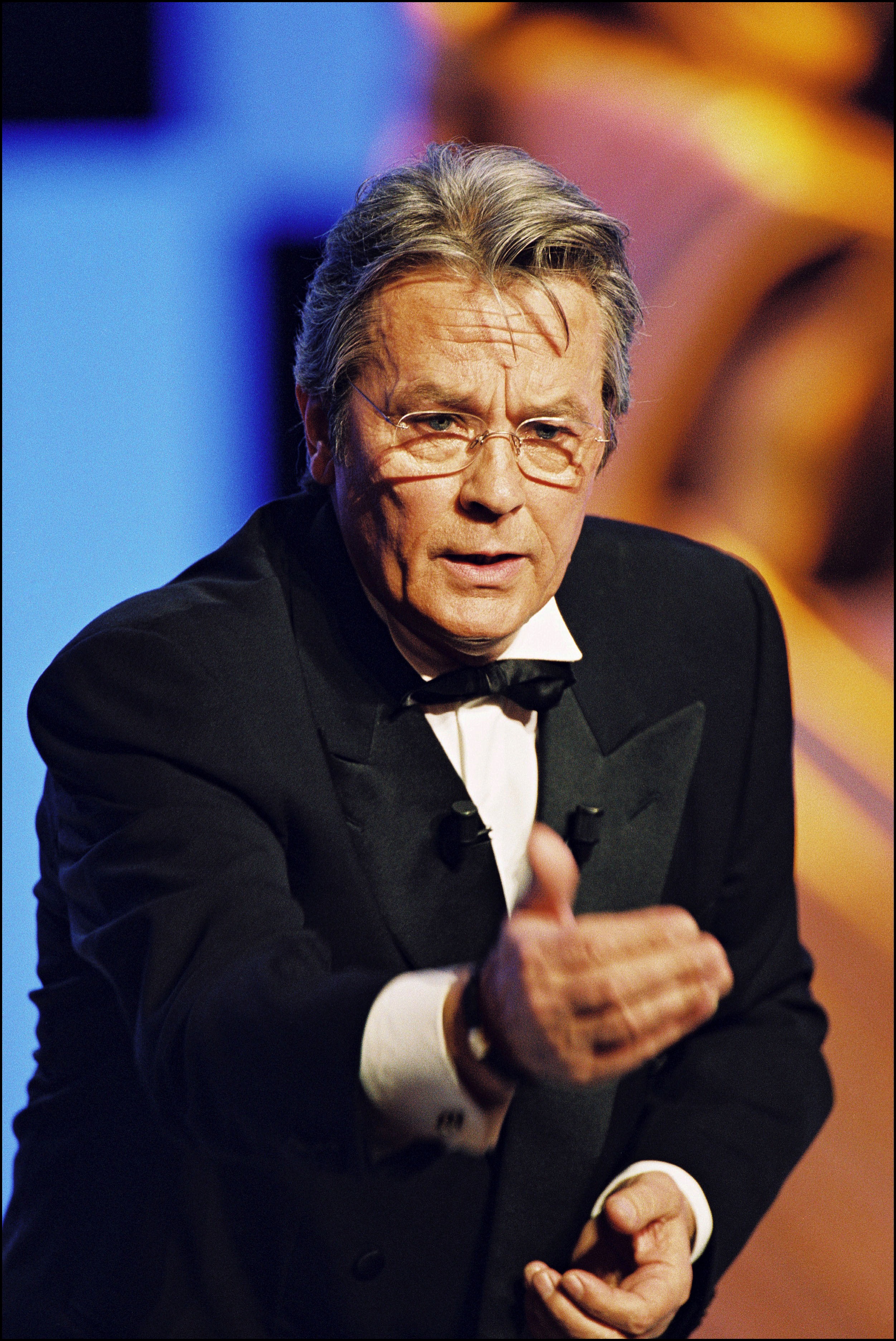 That same year, Delon brought gravity and polish to the 25th César Awards in Paris, cutting a striking figure in a black tuxedo and bow tie. His posture, direct gaze, and steely expression reflected a man deeply rooted in tradition — commanding the room not with flash, but with sheer presence. He aged not by softening, but by sharpening.