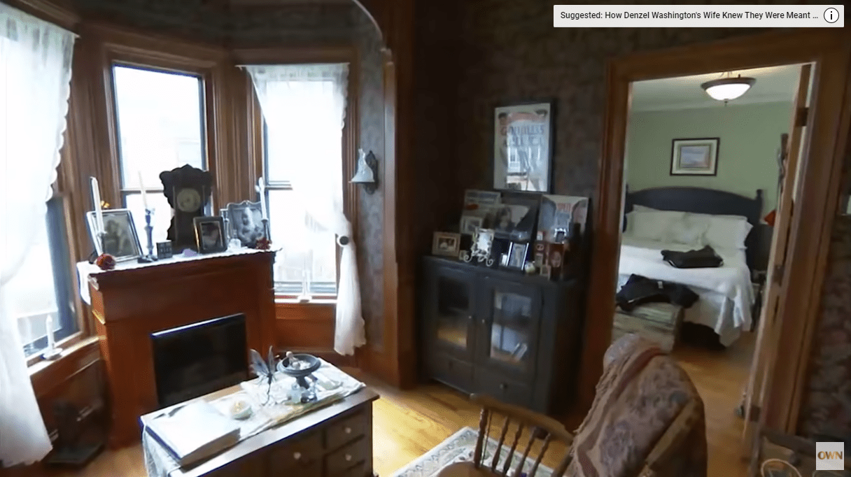 Melissa Gilbert and Tim Busfield's dark-themed living space that features a fireplace, a brown drawer and a rocky chair. / Source: YouTube/@OWN