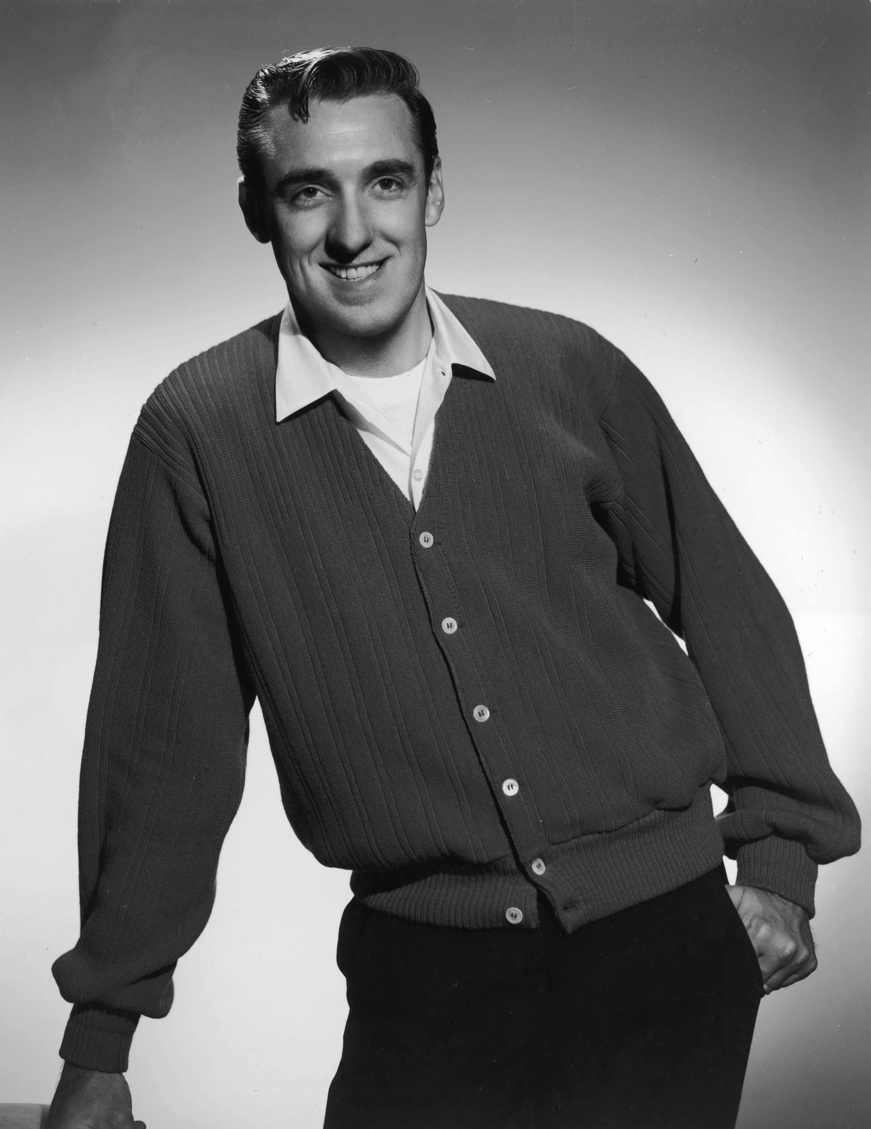 A studio portrait of singer Jim Nabors wearing a cardigan sweater and posing with one hand in his pocket in 1965. | Source: Getty Images