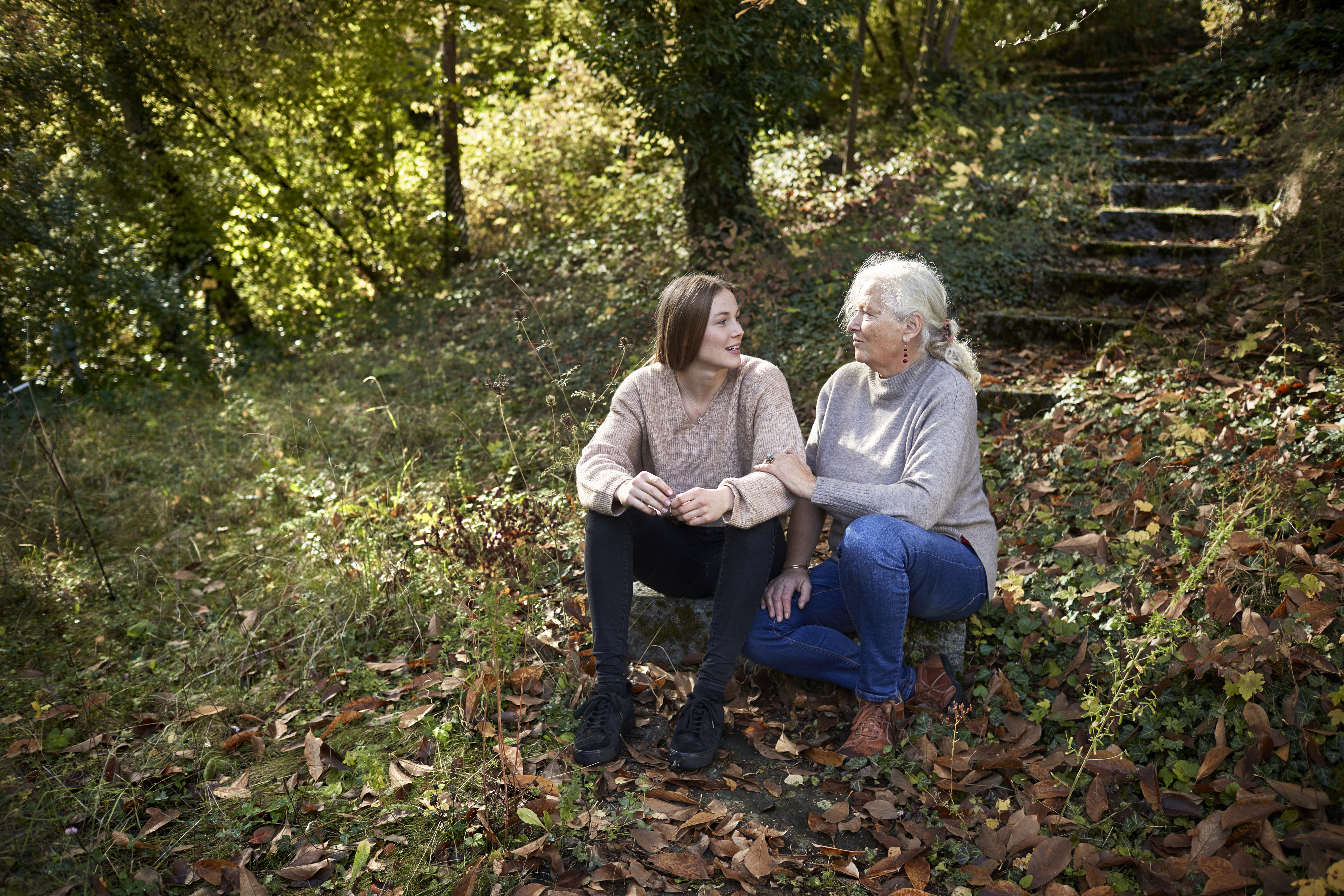 Grandmother and adult granddaughter sitting in autumnal garden | Source: Getty Images