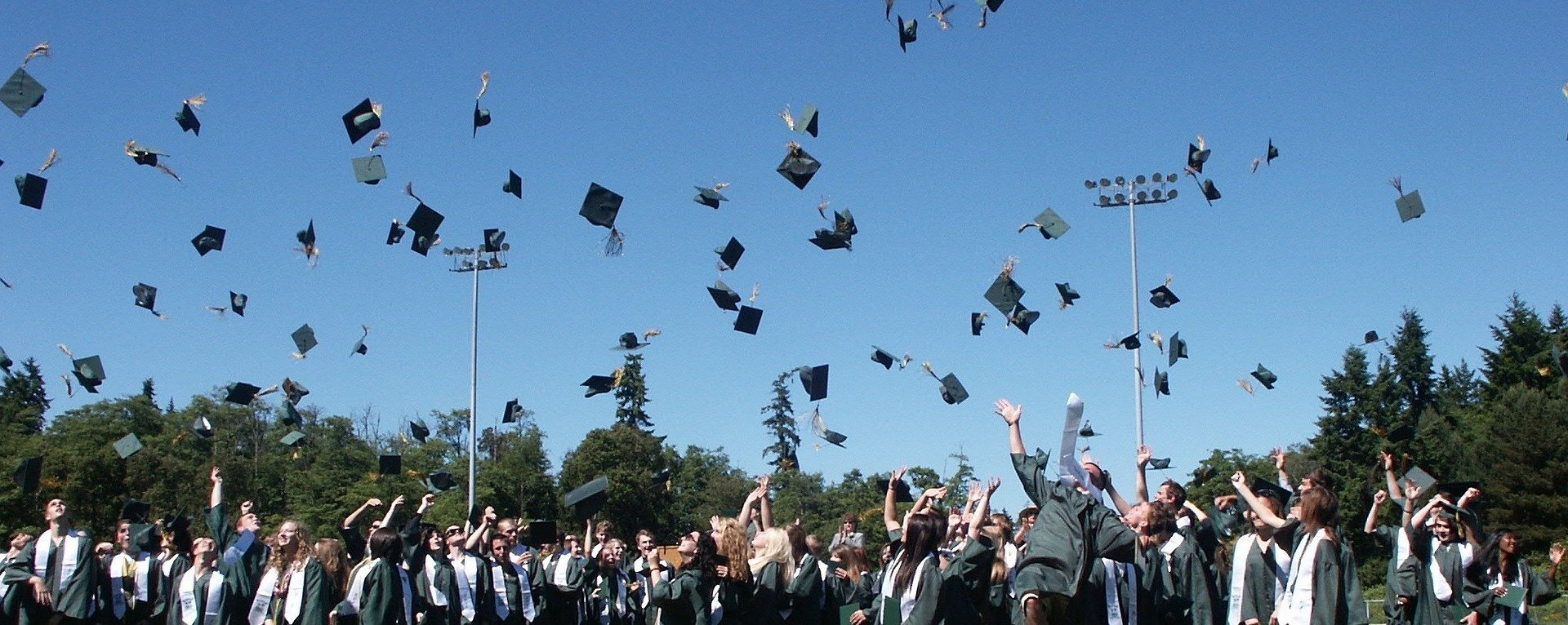 A bunch of high school graduates throws their graduation caps up in the air while celebrating outdoors | Photo: Pixabay/Gillian Callison