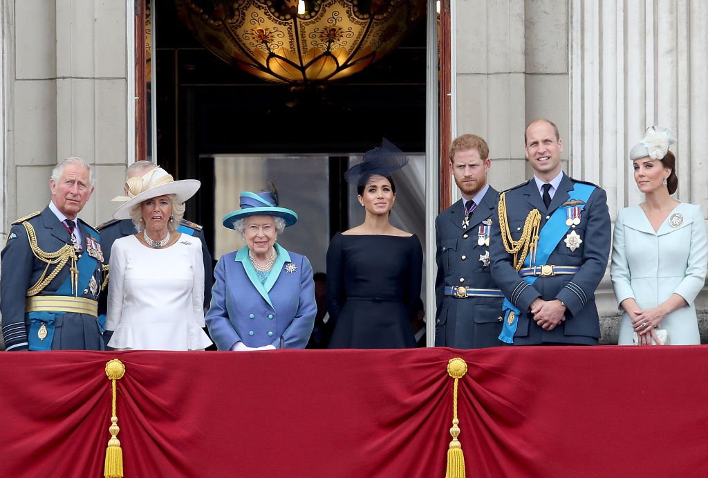 Le prince Charles, Camilla, la reine Elizabeth II, Meghan, le prince Harry, le prince William et Catherine, regardent le défilé aérien de la RAF sur le balcon de Buckingham Palace, alors que les membres de la famille royale assistent aux événements marquant le centenaire de la RAF, le 10 juillet 2018. | Source : Getty Images