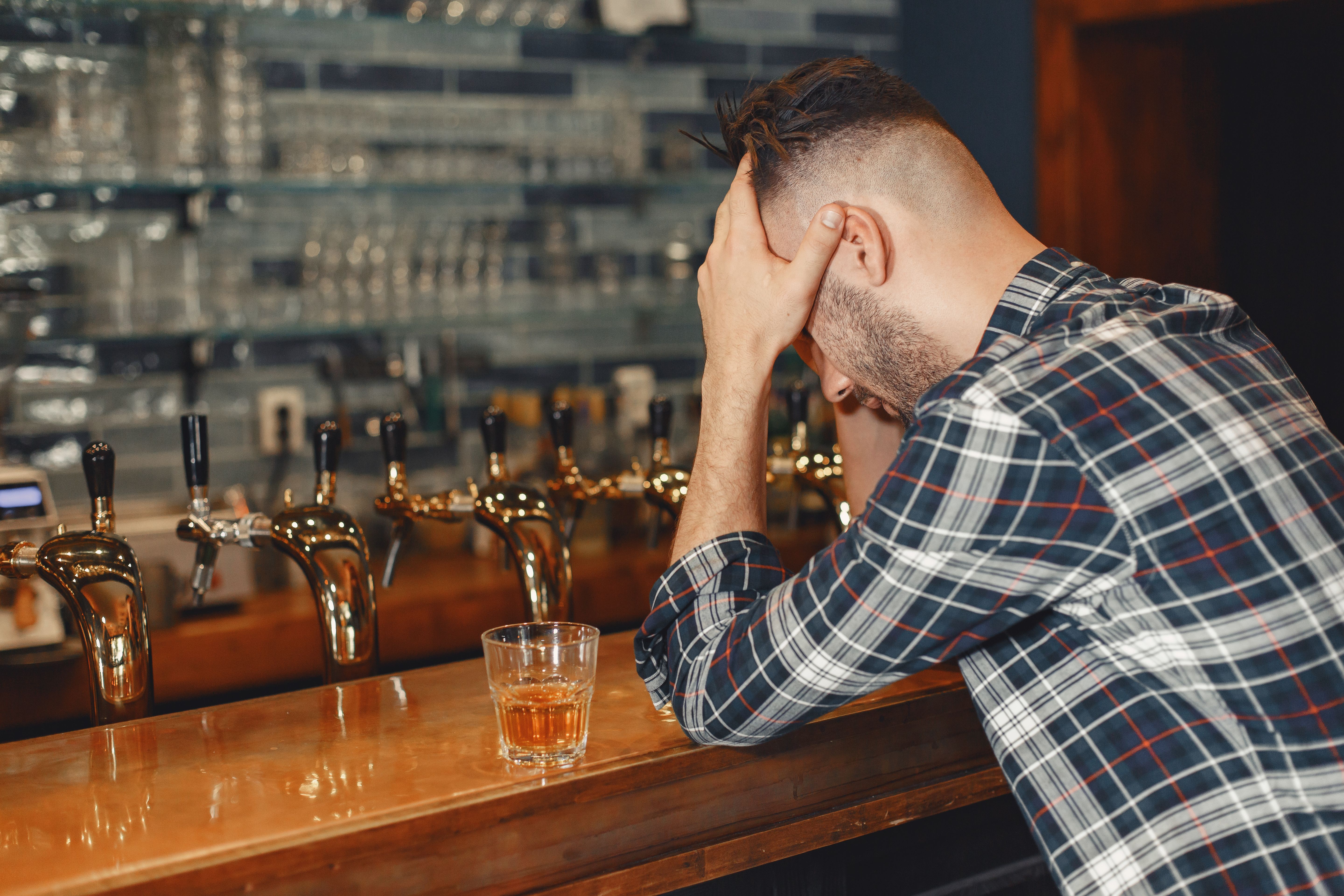 Man sitting at a bar with his head down | Source: Pexels