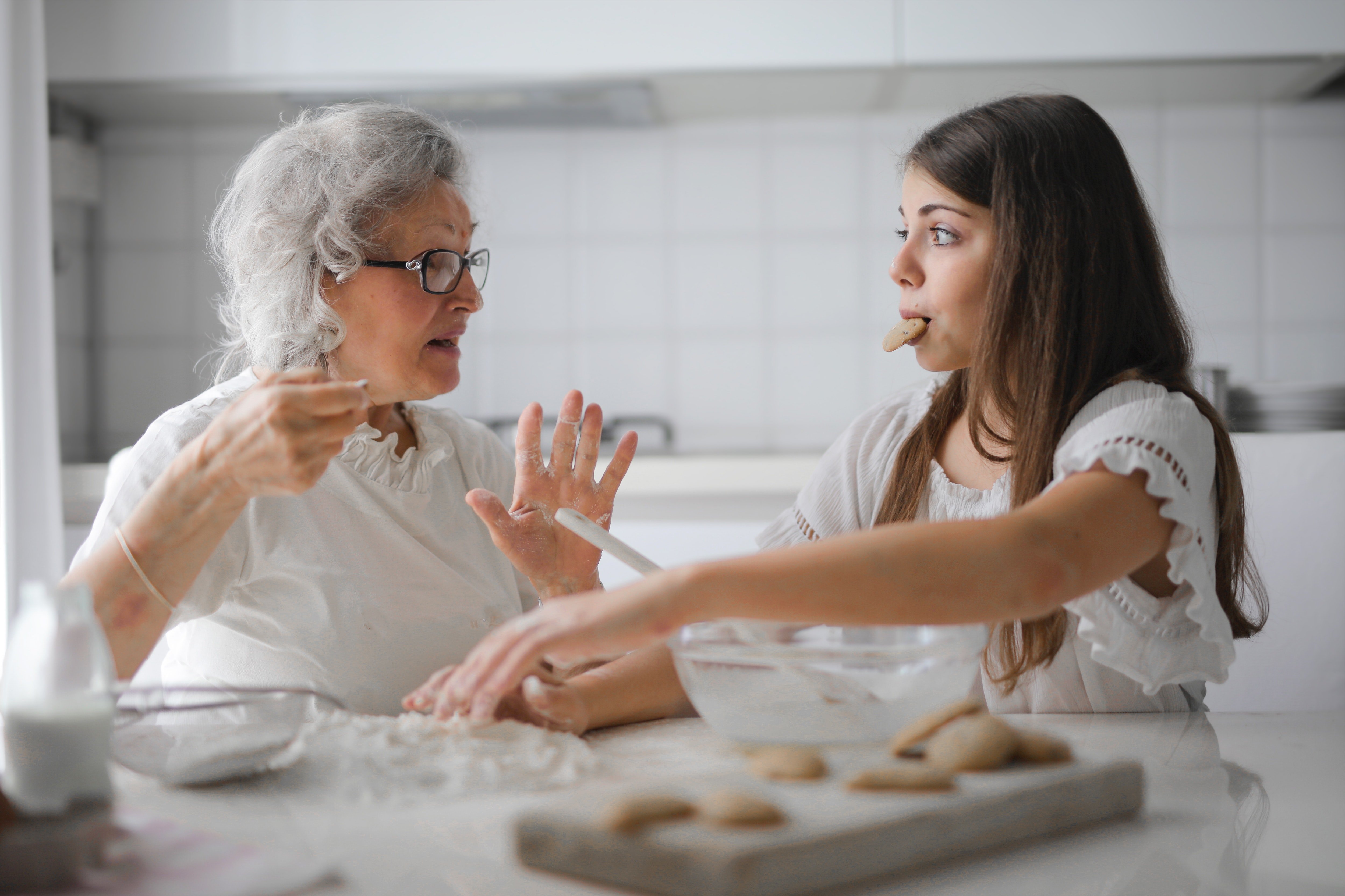 An elderly lady is seen having a conversation with a young girl in the kitchen. | Source: Pexels