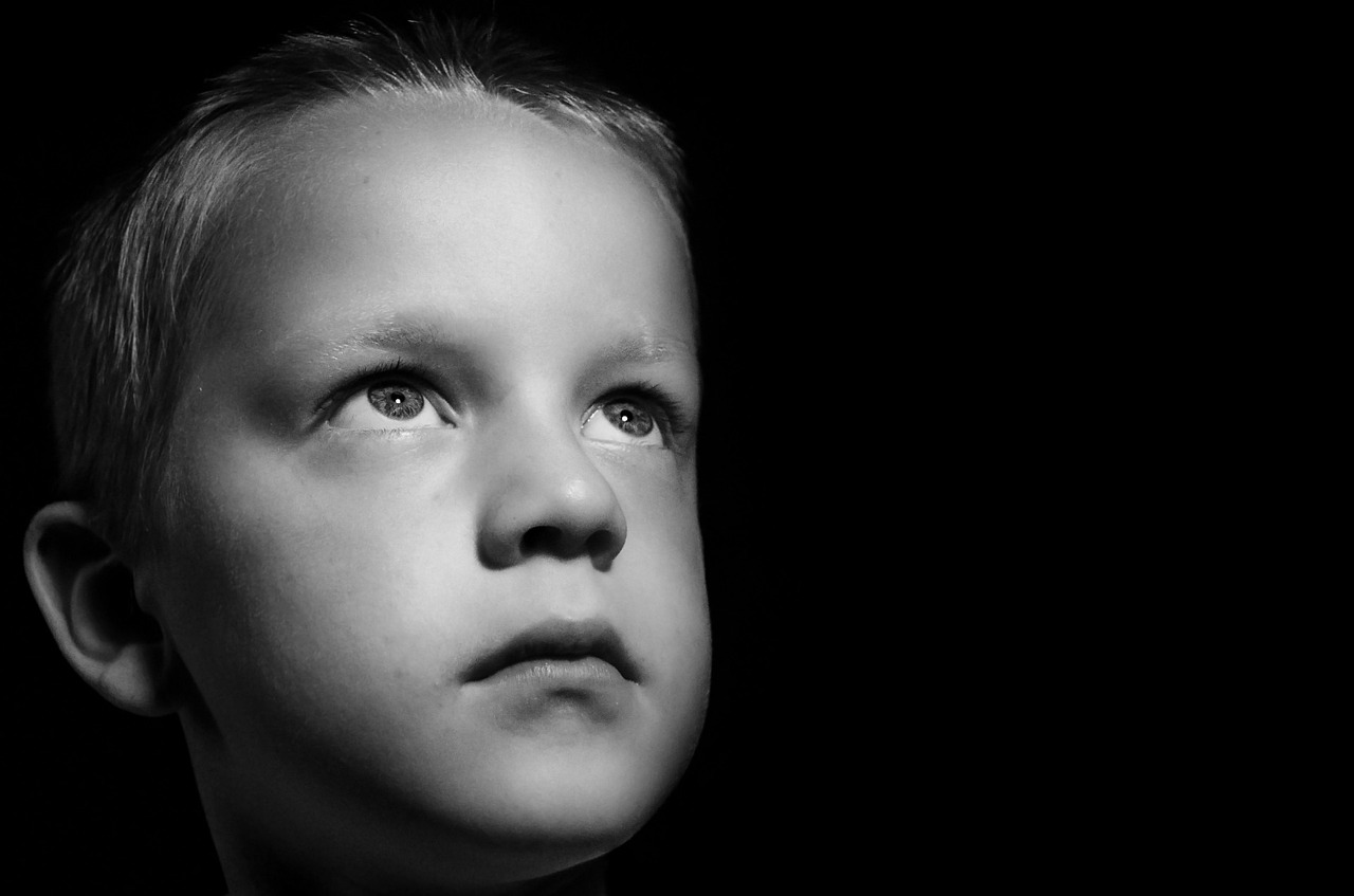 Grayscale of a sad little boy looking up | Source: Pixabay