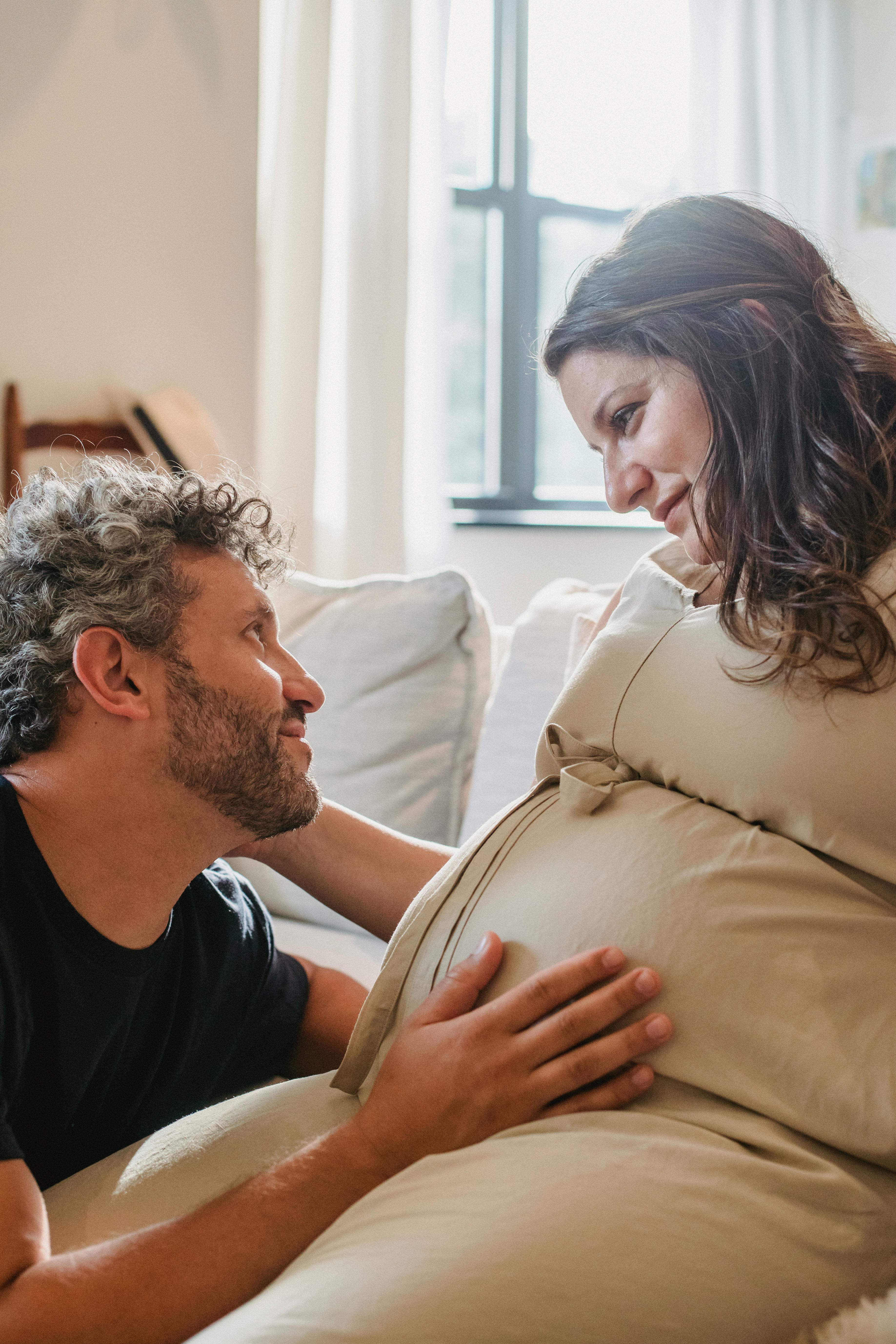 Man touching his pregnant wife's belly as they stare at each other | Source: Pexels