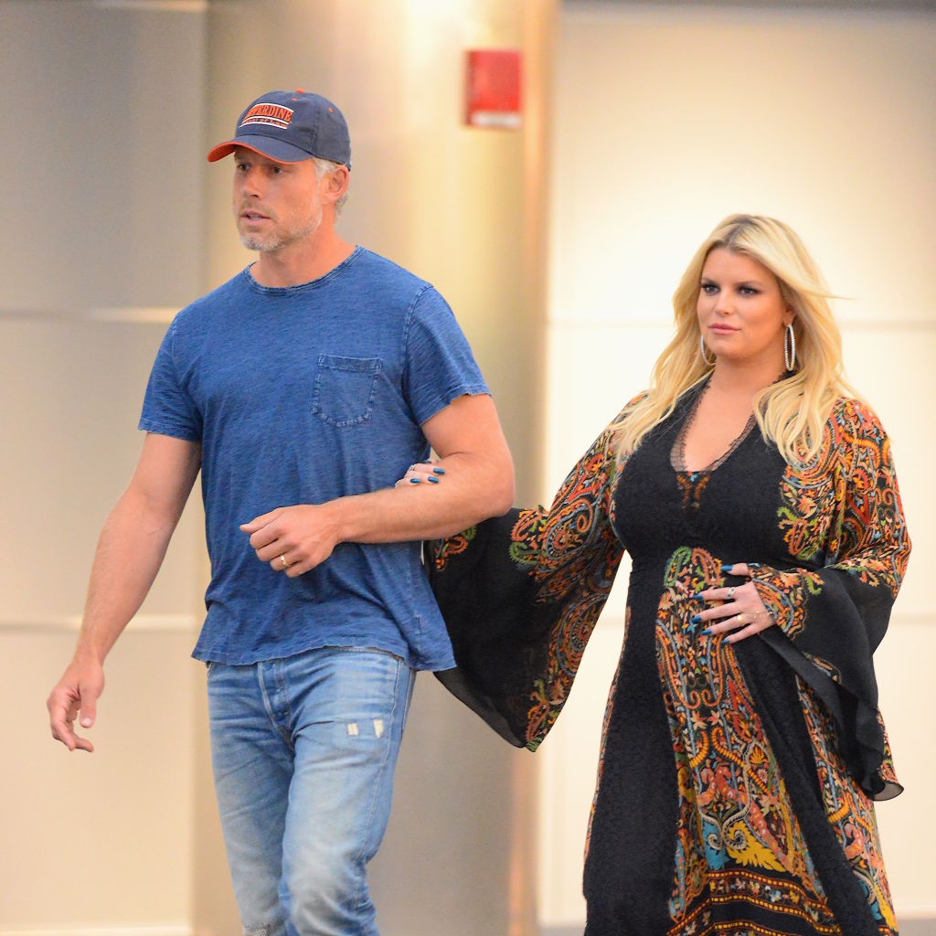 Jessica Simpson and husband Eric Johnson were spotted at JFK Airport in New York City. She wore a patterned kimono over a black dress and held her baby bump, leaning into relaxed maternity style while Johnson kept it casual.