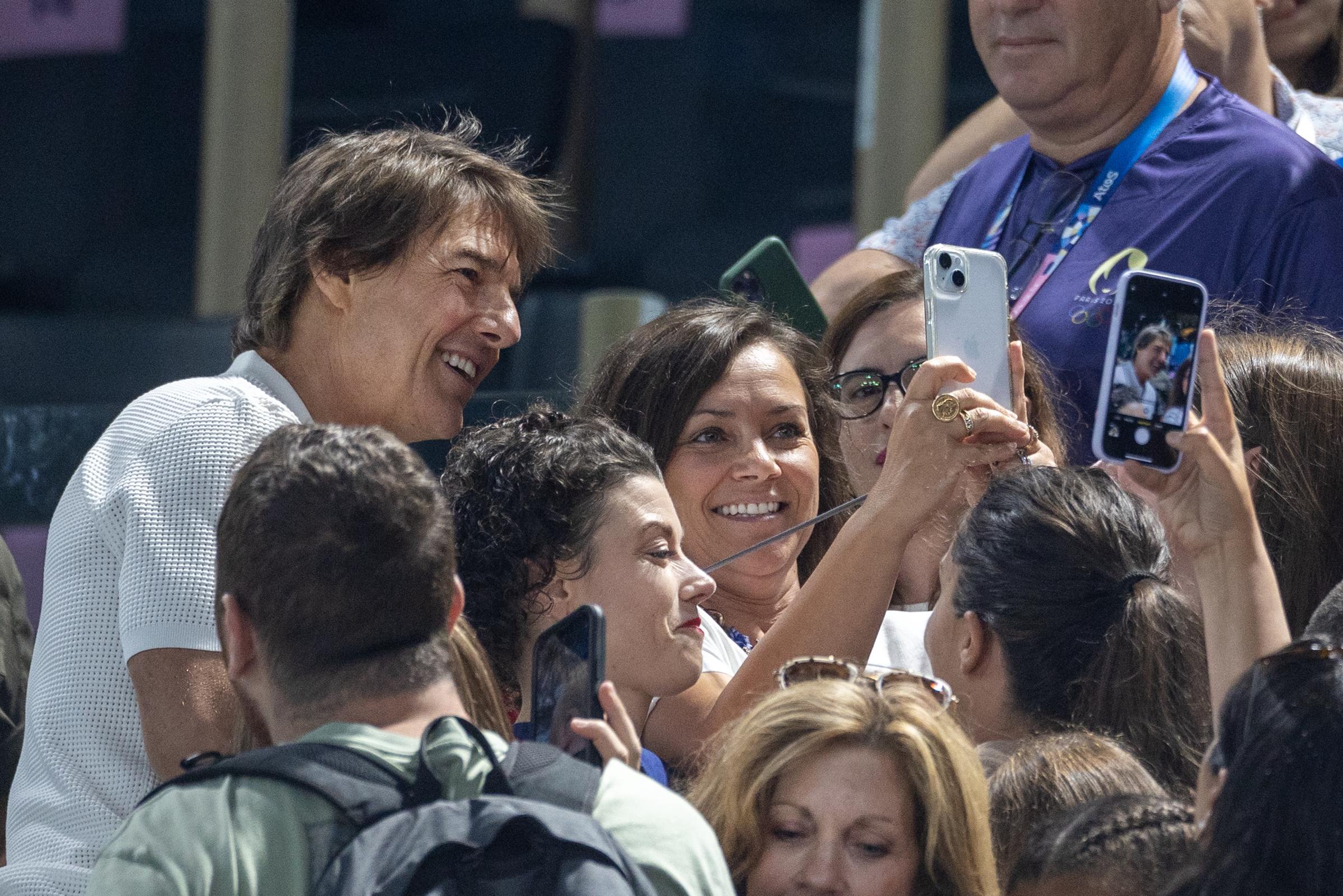 Tom Cruise posing for photographs with spectators during the Artistic Gymnastics Women's Qualification event during the Paris 2024 Summer Olympic Games on July 28 in France. | Source: Getty Images