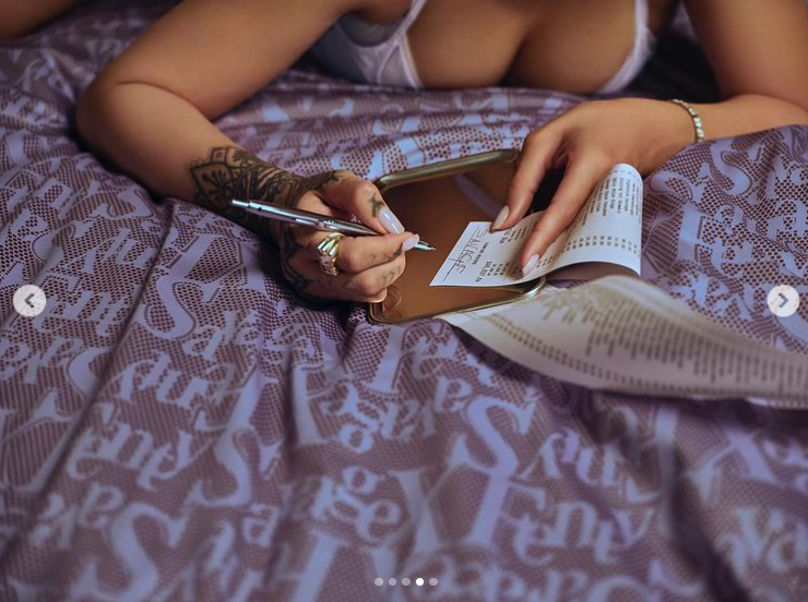 Rihanna wears lilac lingerie as she writes a check. | Source: Instagram/badgalriri