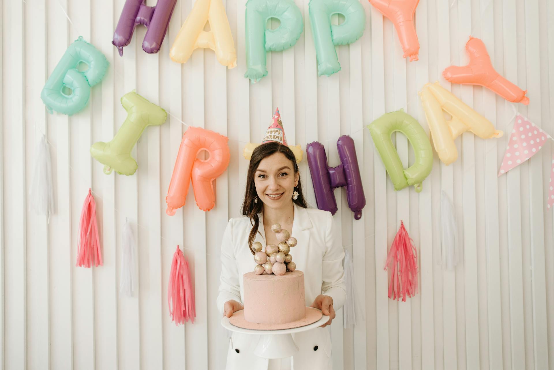 A woman holding a cake and wearing a party hat | Source: Pexels