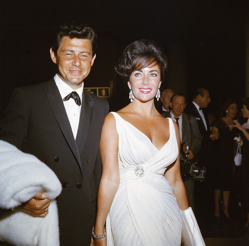 British native Elizabeth Taylor and her fourth husband American singer and actor Eddie Fisher arrive at a formal event in 1962 | Photo: Getty Images