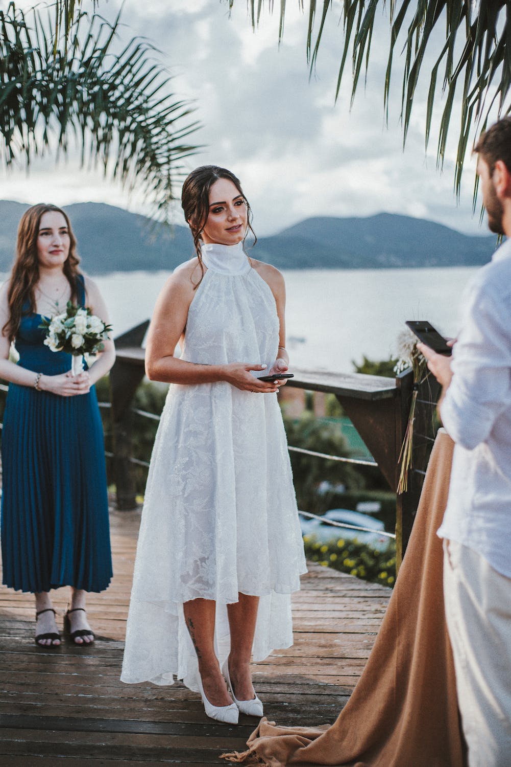 A bride in white and her maid of honor standing in front of the groom in white | Source: Pexels