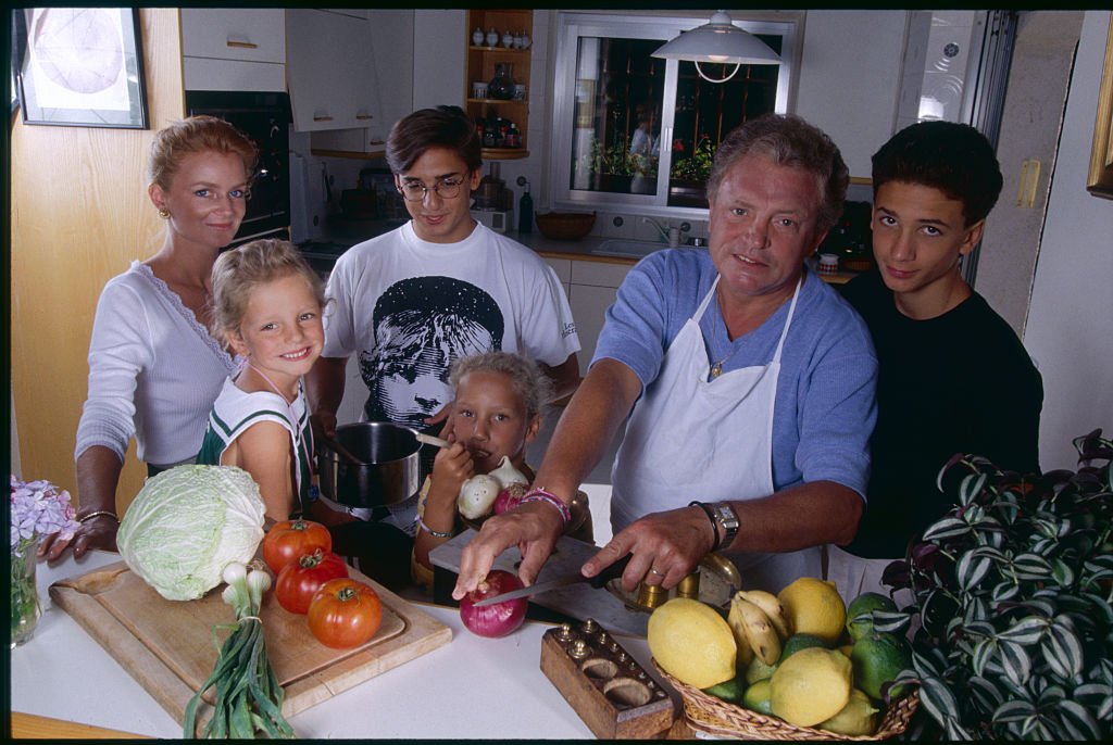 Jacques Martin posant dans une cuisine avec sa femme Céline, ses fils, Frédéric et Jean Baptiste et ses filles, Judith et Jeanne Marie. | Photo : Getty Images