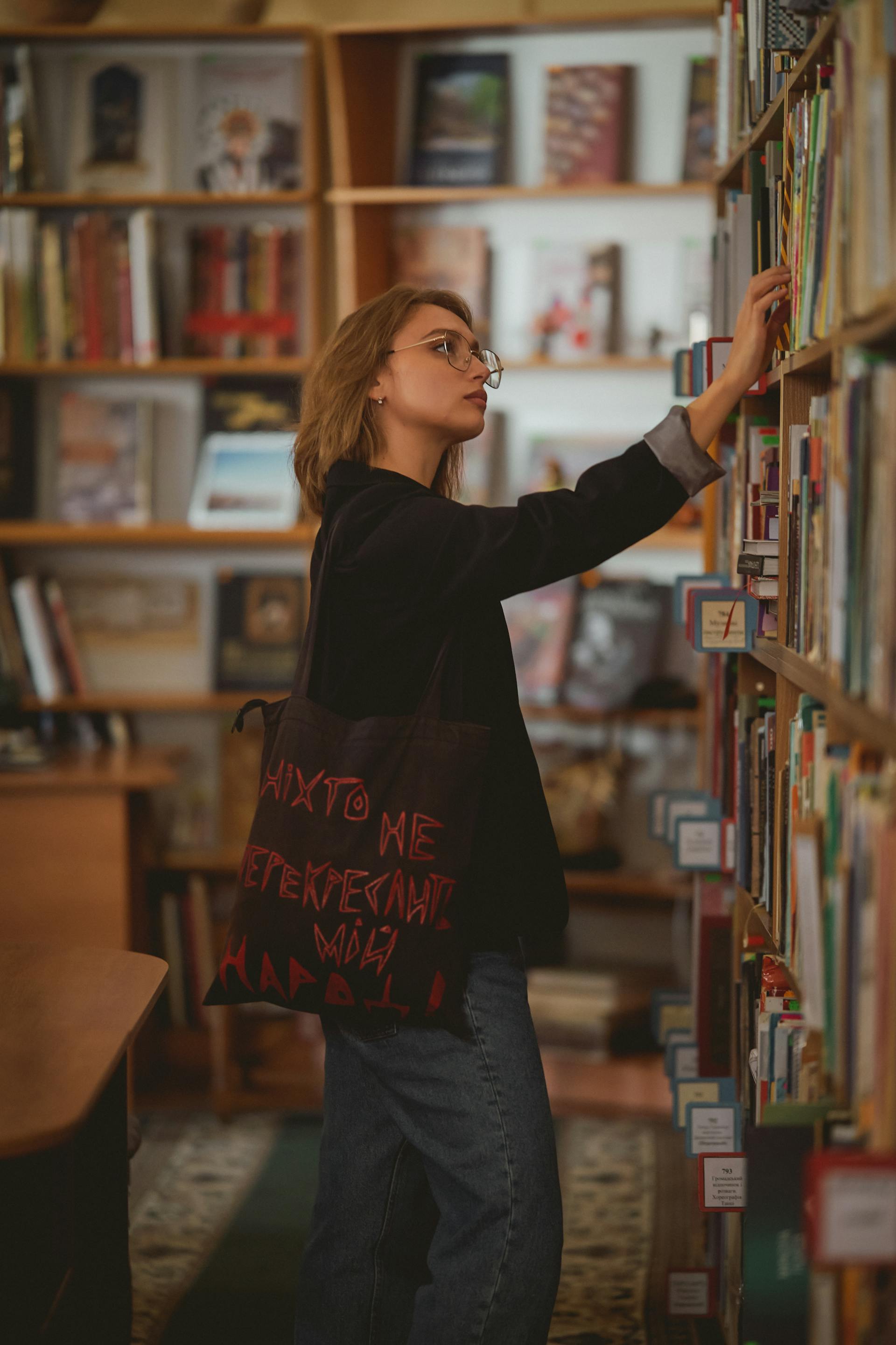 A young woman picking a book from a bookshelf | Source: Pexels