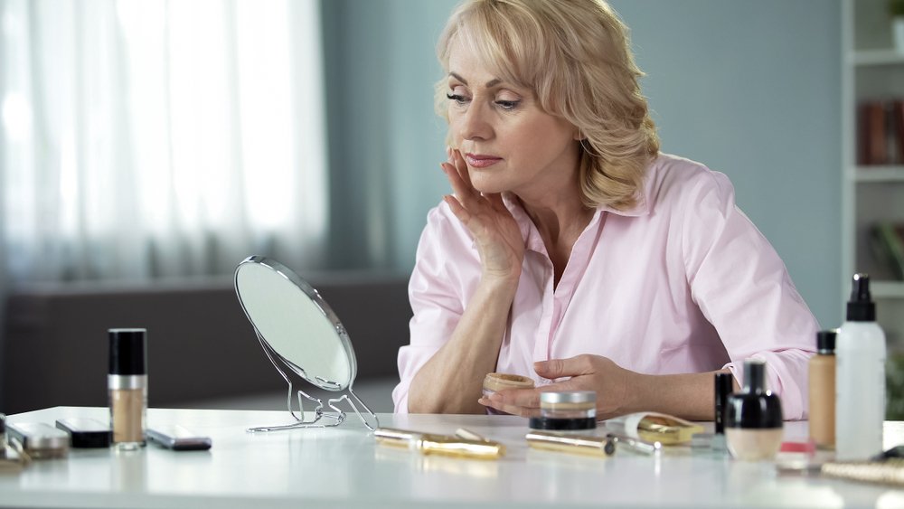 Señora maquillándose frente al espejo. | Foto: Shutterstock
