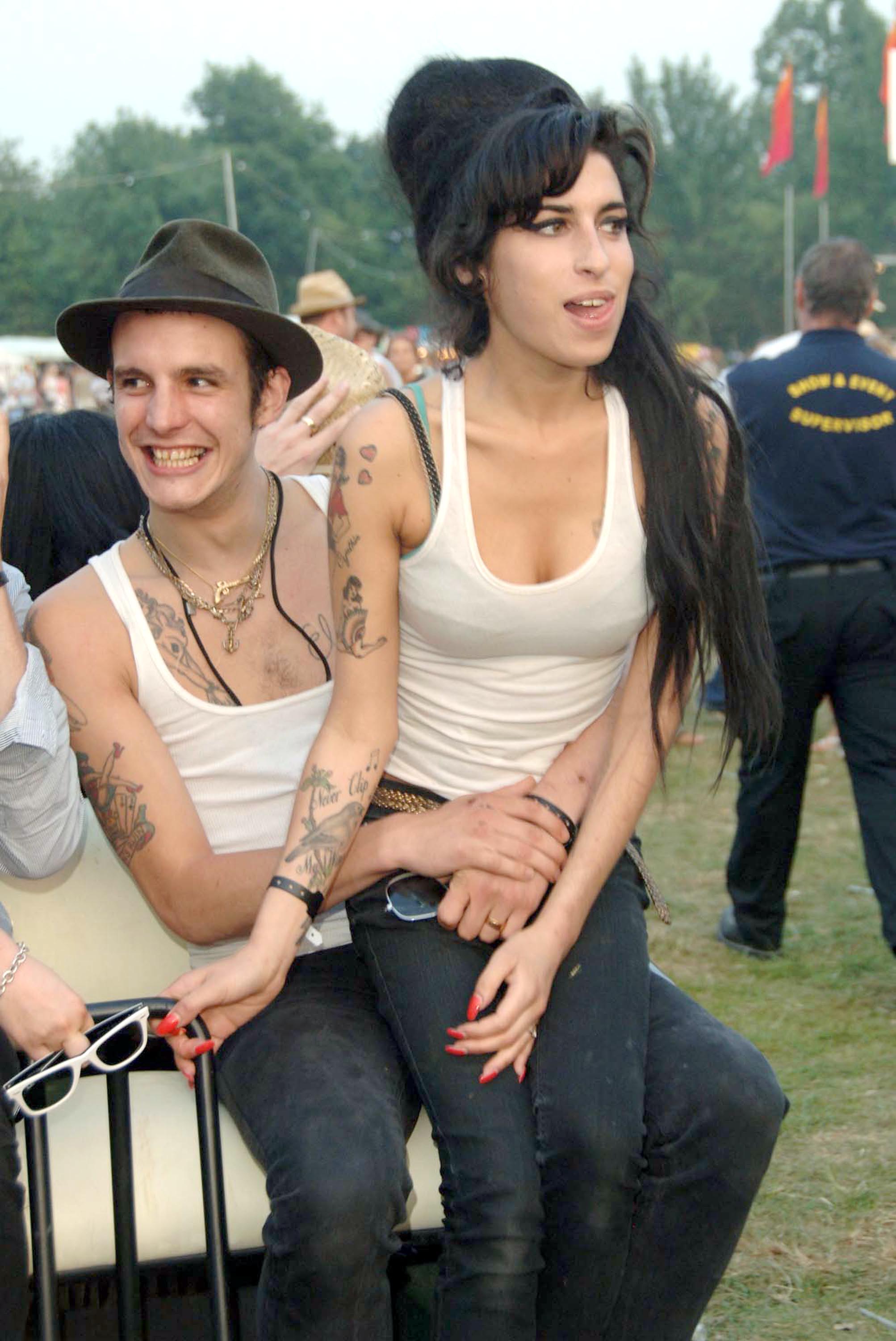 Blake Fielder-Civil and Amy Winehouse are pictured backstage at the Isle of Wight Festival on June 9, 2007, during the height of the singer's global fame and one of the most volatile periods of their relationship. The image captures a moment of apparent closeness between the pair, whose intense and often destructive bond would come to define much of Winehouse's public narrative.