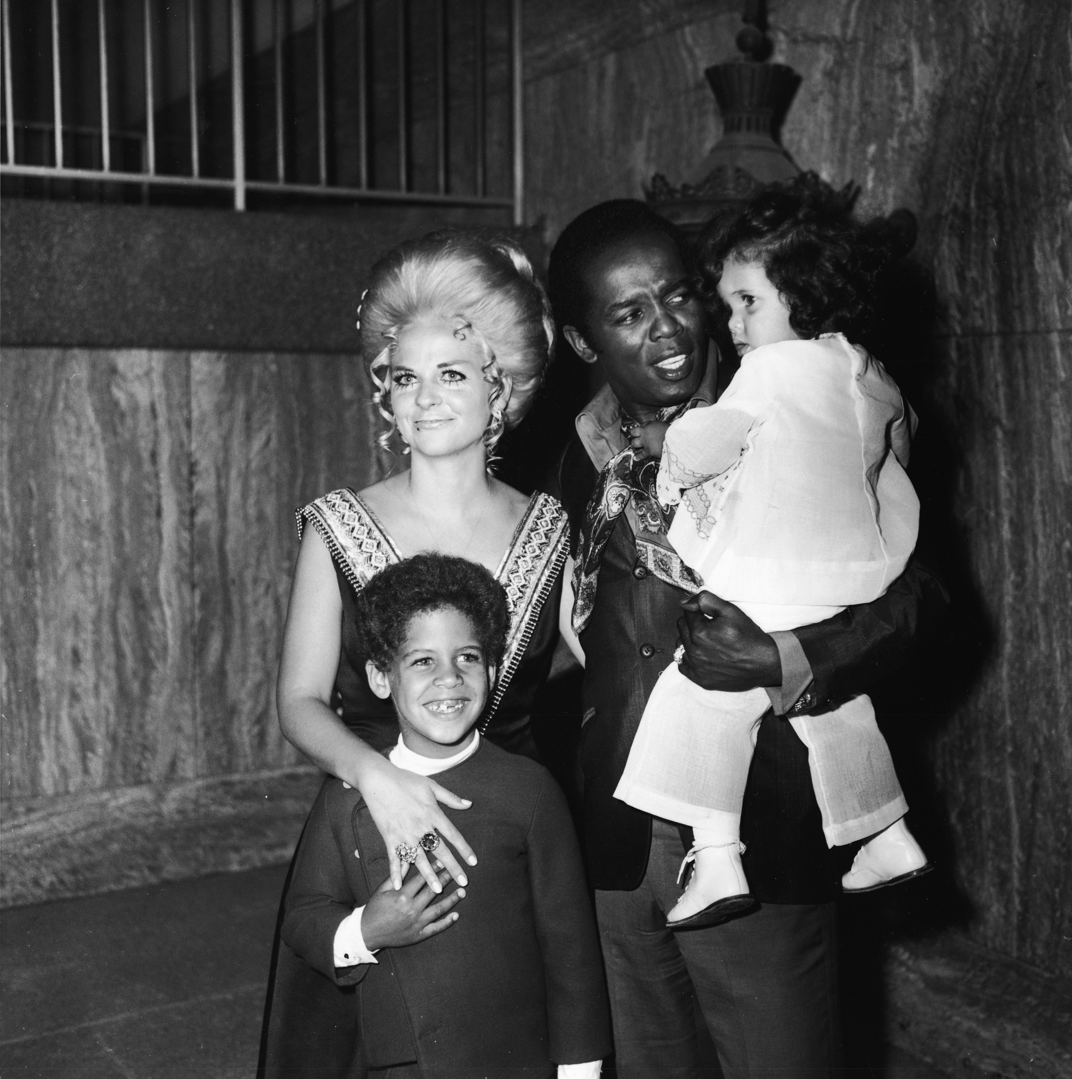 Lou Rawls holds his daughter Louanna as his wife Lana Jean and son Lou Jr. stand with him at the opening of his stint at the Century Plaza Hotel, Los Angeles, California, 1973. | Photo: Getty Images