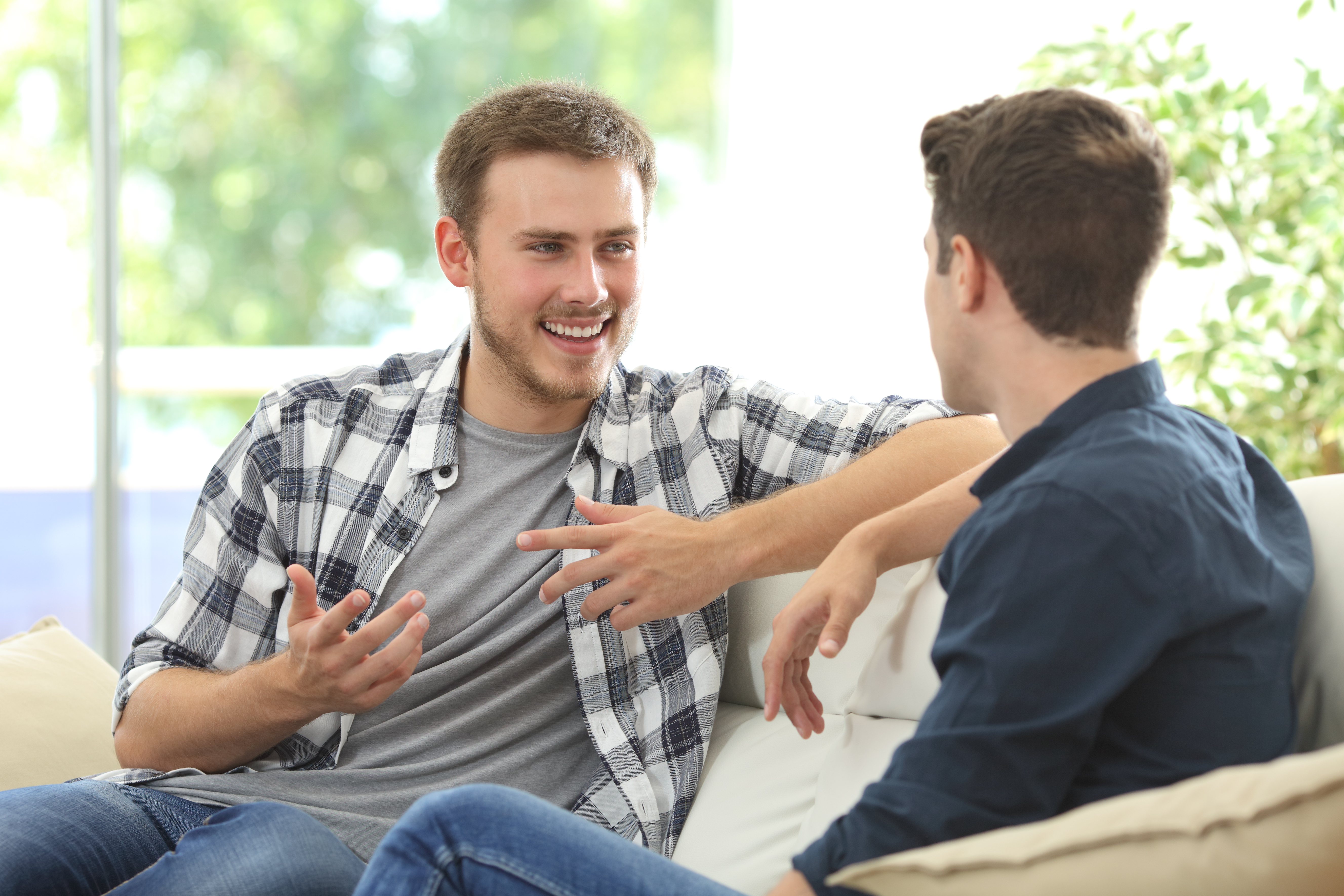 Two men talking while sitting on a couch at home | Source: Shutterstock