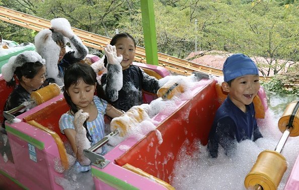 Young kids pictured in a roller coaster with built-in bathtubs filled with hot spring-water bubbles | Photo: Getty Images