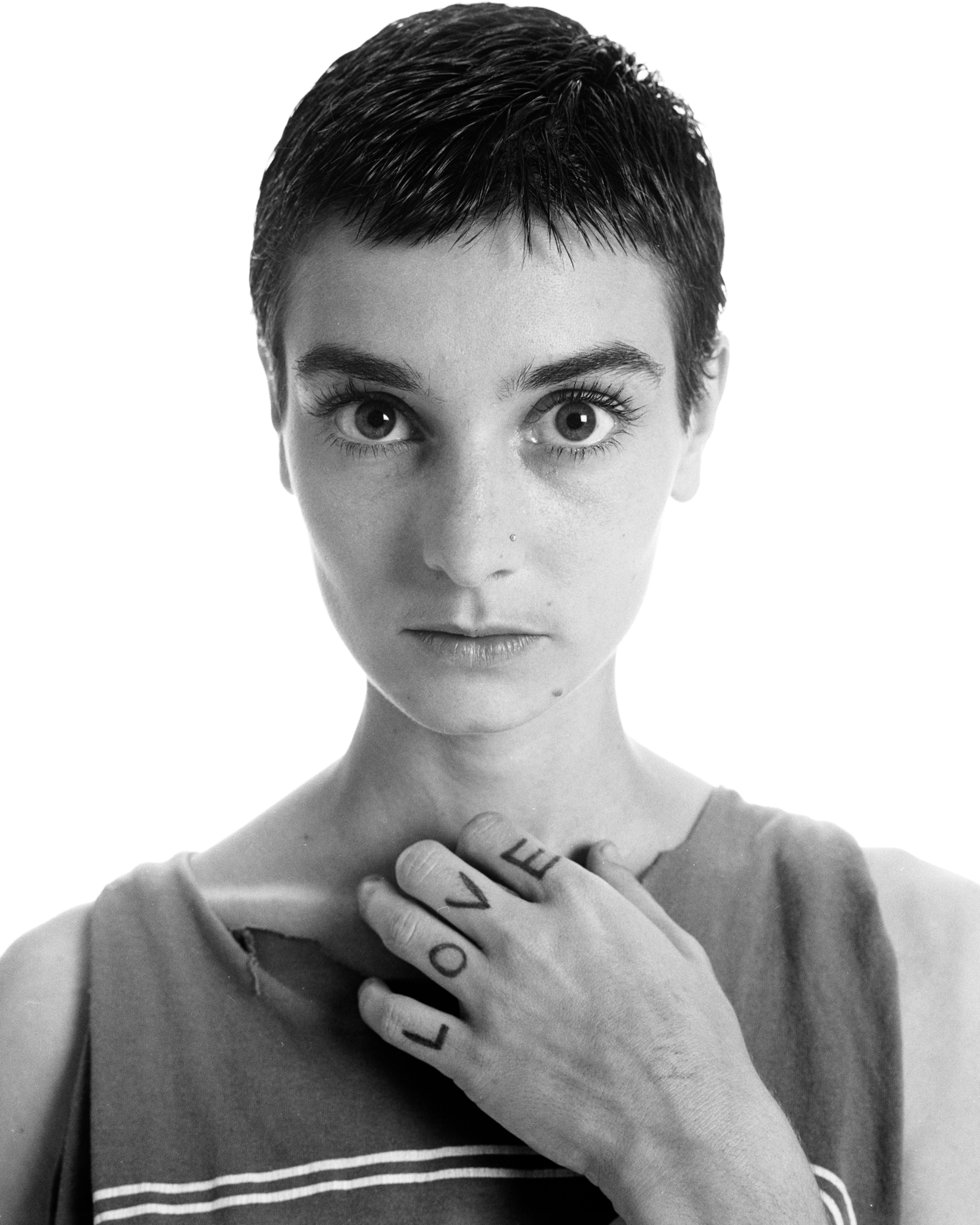 Sinéad O'Connor posing in a black and white photo with the word "love" written on her fingers, 1994 | Source: Getty Images
