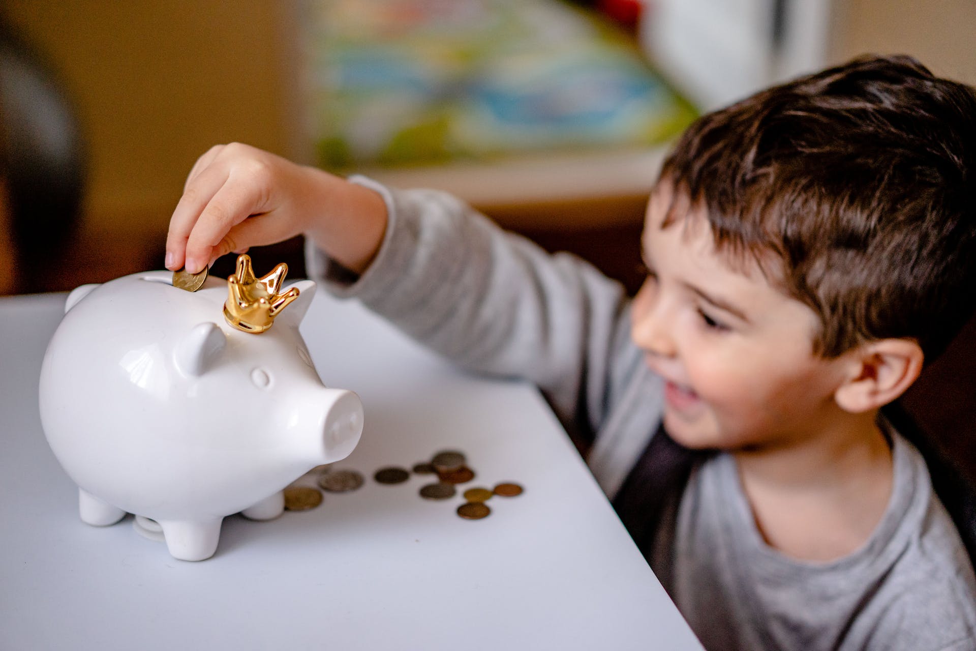 A boy dropping coins in a piggy bank | Source: Pexels