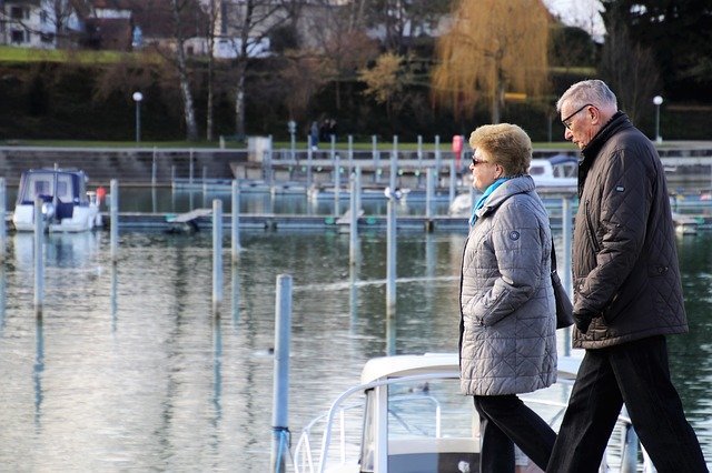 A senior couple walks along a marina | Photo: Pixabay