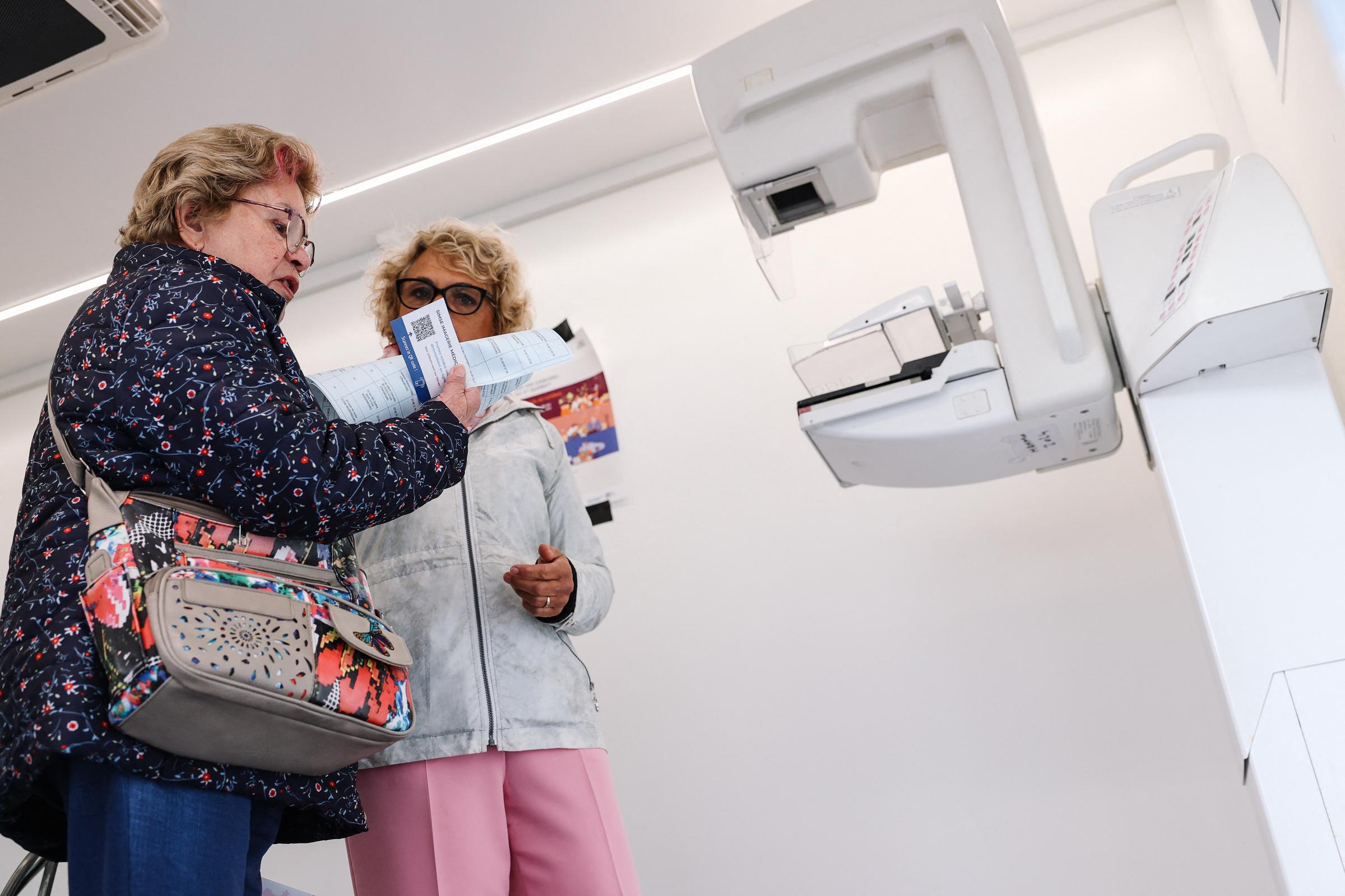 A French radiographer gives a woman information about a mammography inside a "breast bus" set to raise awareness of breast cancer and screenings in Strasbourg, eastern France, on October 9, 2024 | Source: Getty Images