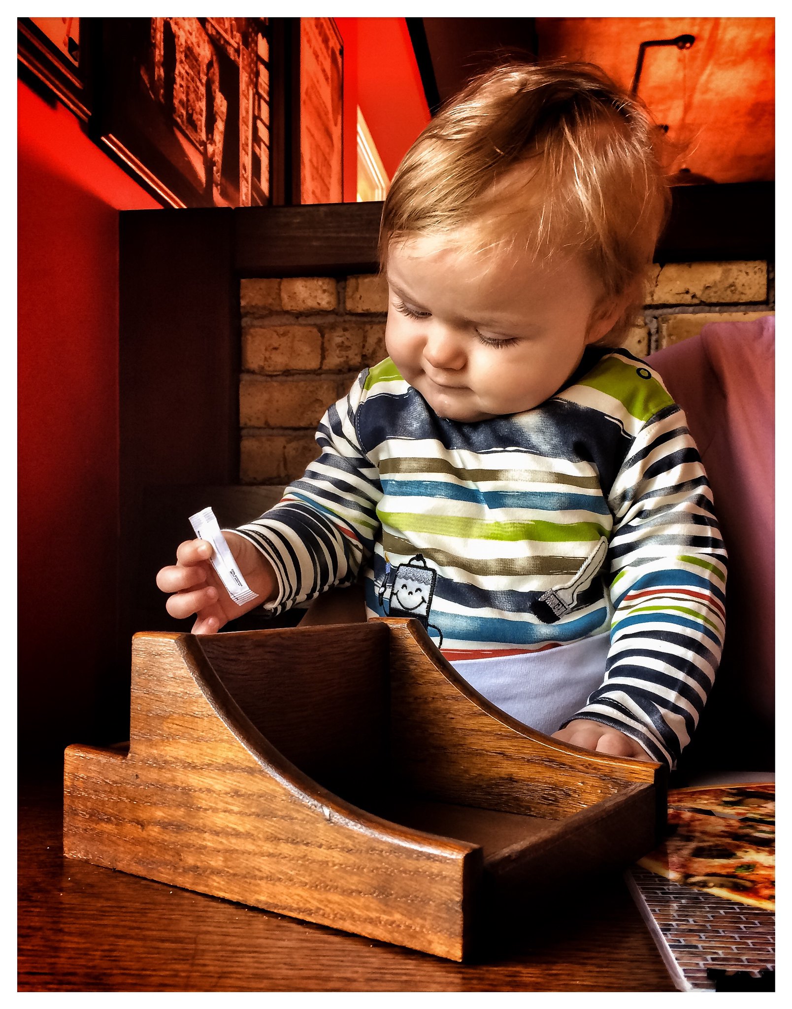 A little boy playing with a sugar sachet in a restaurant | Source: Flickr