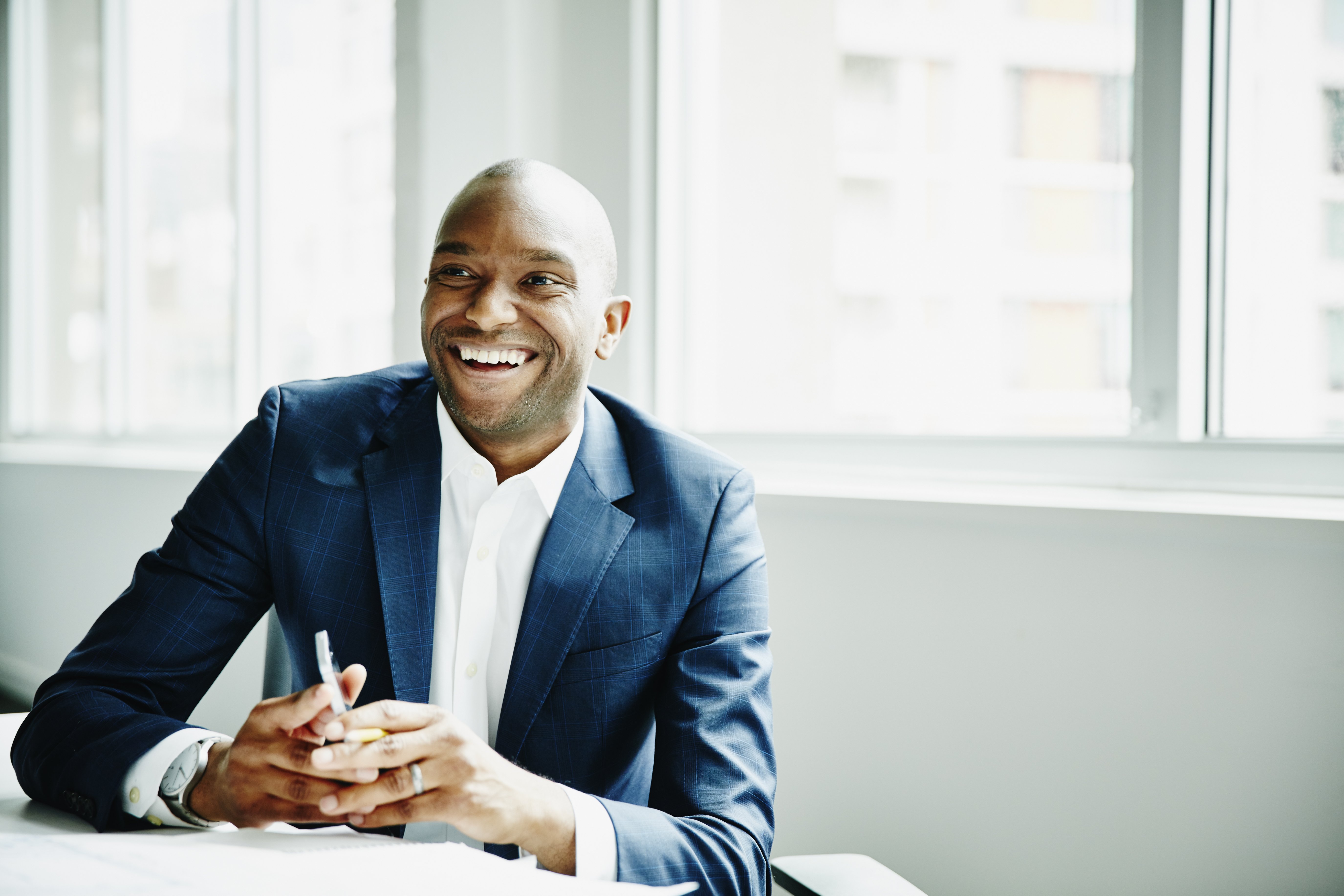 Smiling businessman in discussion at workstation in office|Photo: Getty Images