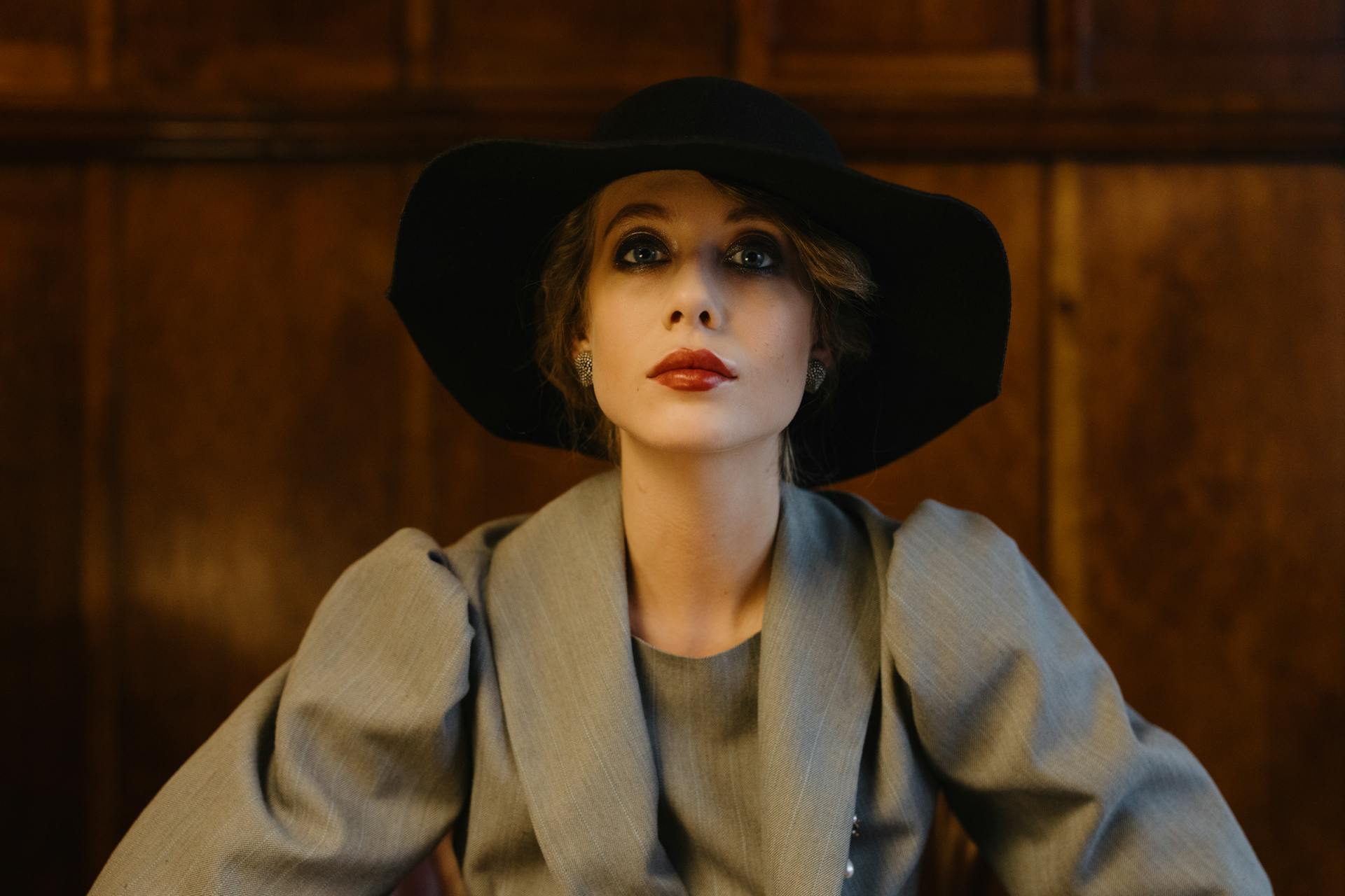 Una mujer seria con chaqueta gris y sombrero negro mira al frente | Fuente: Pexels