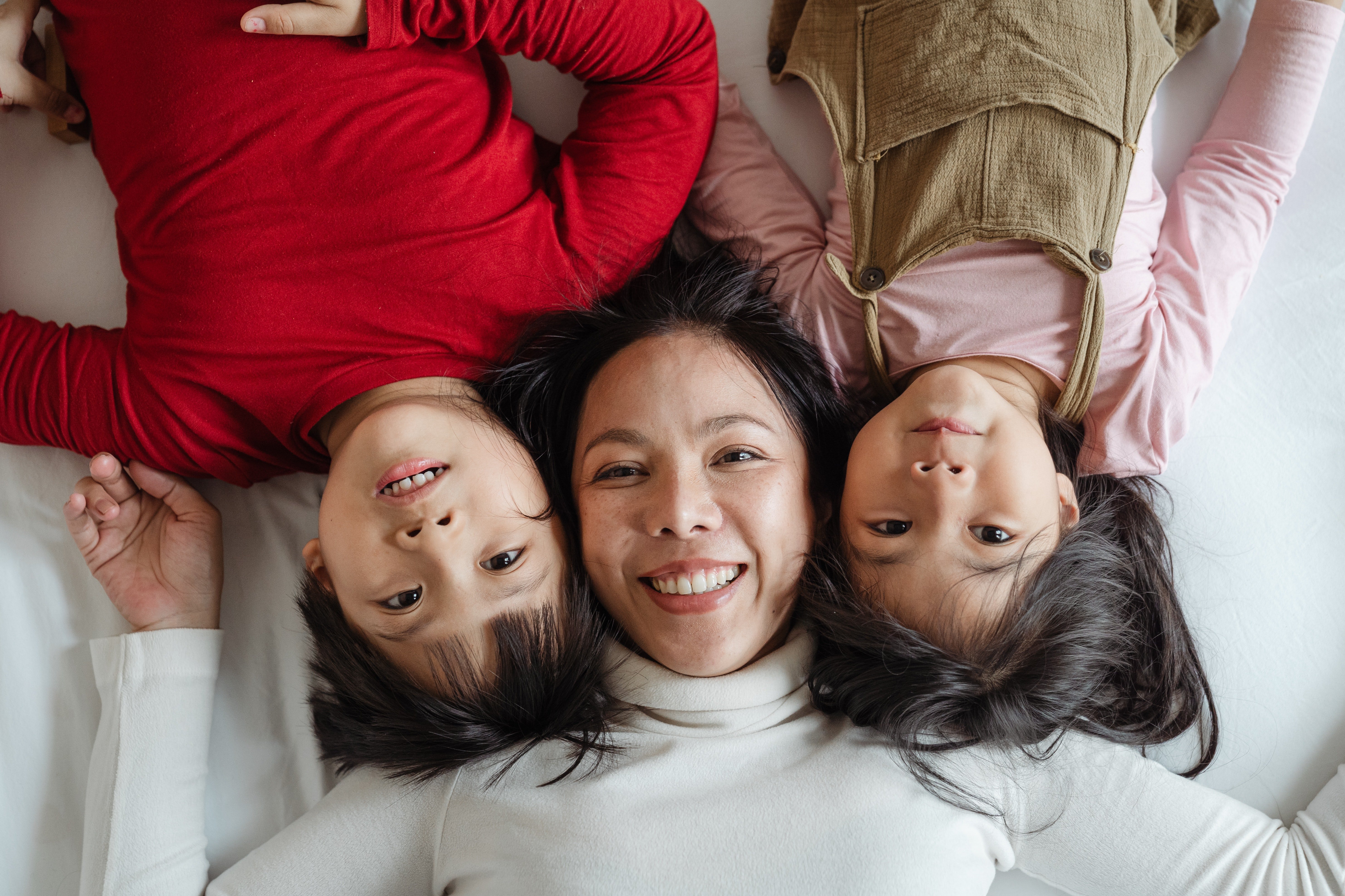 Mujer sonriente con sus dos hijos. | Foto: Pexels