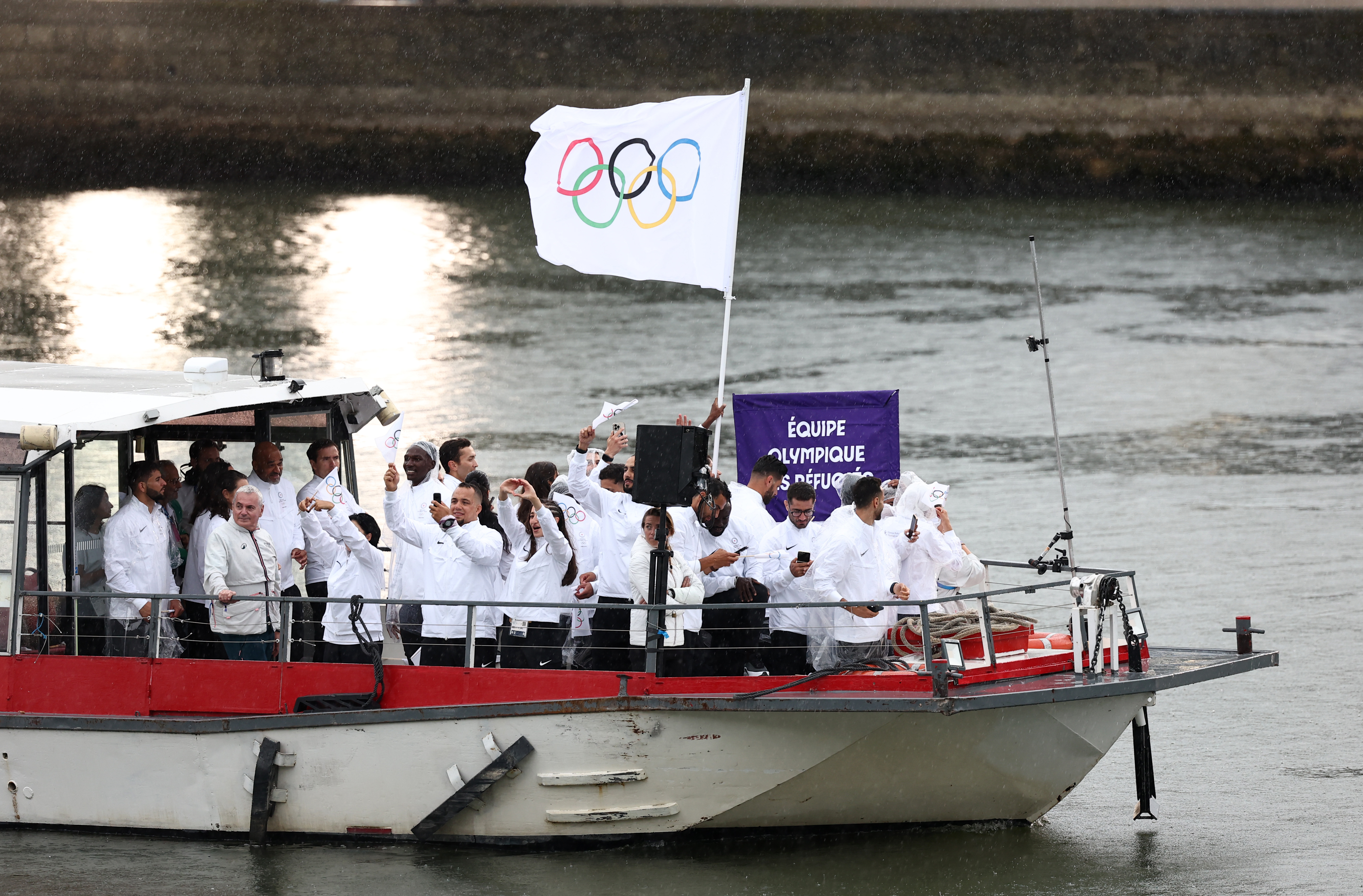 Athletes from Refugee Olympic Team delegation sail in a boat along the river Seine as rain starts at the start of the opening ceremony of the Paris 2024 Olympic Games in Paris, France, on July 26, 2024. | Source: Getty Images