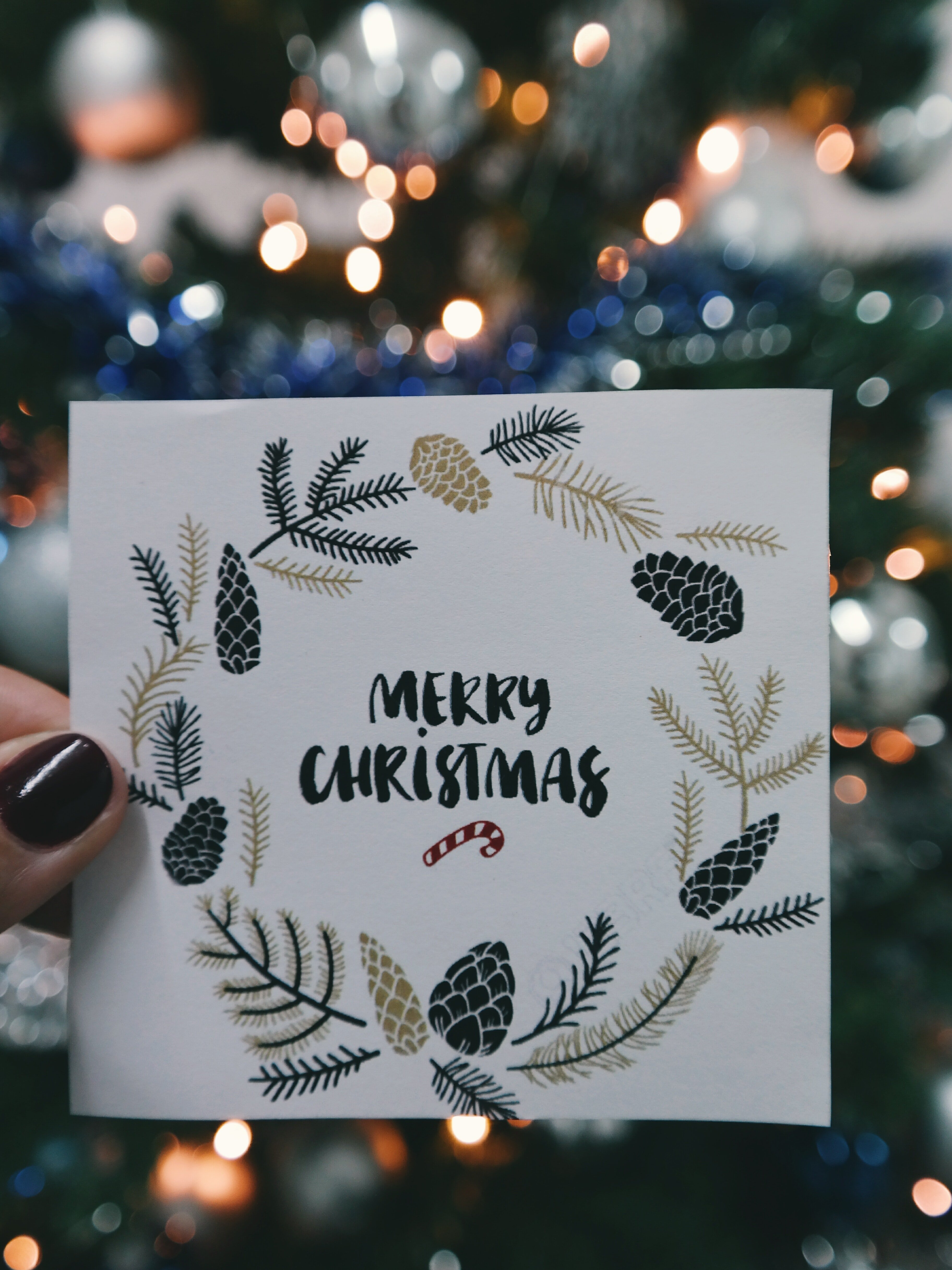 Christmas card in front of tree | Photo: Pexels.com