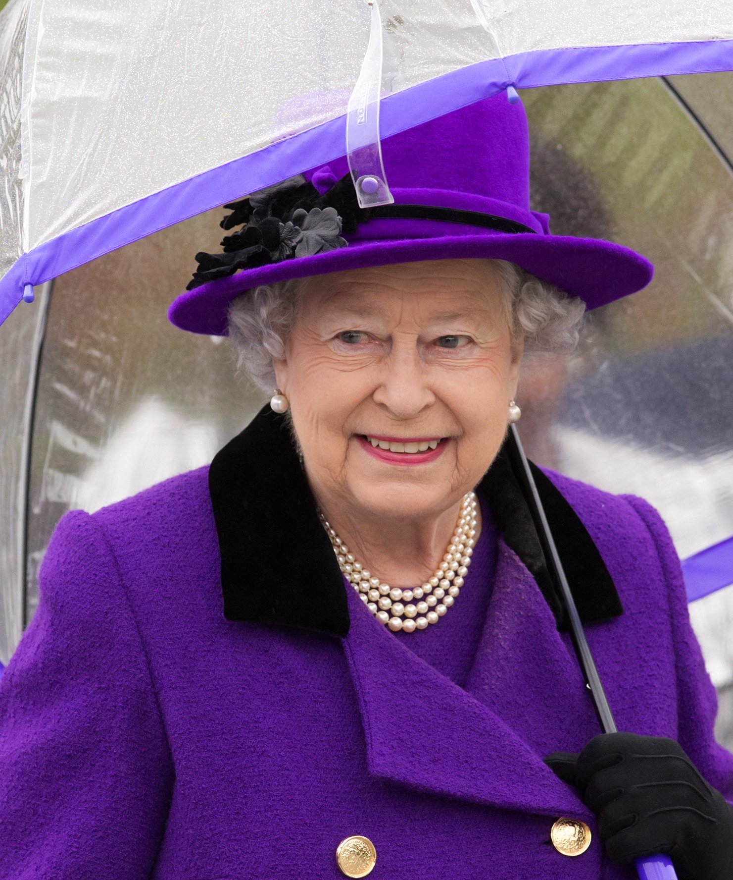  Queen Elizabeth II shelters under an umbrella as attends the opening of the newly developed Jubilee Gardens on October 25, 2012, in London, England. | Source: Getty Images.