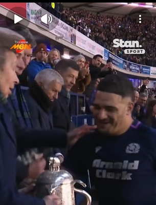 Princess Anne presents the Calcutta Cup to Scotland captain Sione Tuipulotu during the Six Nations clash at Murrayfield on Saturday, February 14, 2026, moments before the now-viral exchange unfolded. The still, taken from a post dated February 17, 2026, captures the calm before the celebratory surge as the silver trophy glints between them and the crowd looks on expectantly. | Source: YouTube/StanSportAU