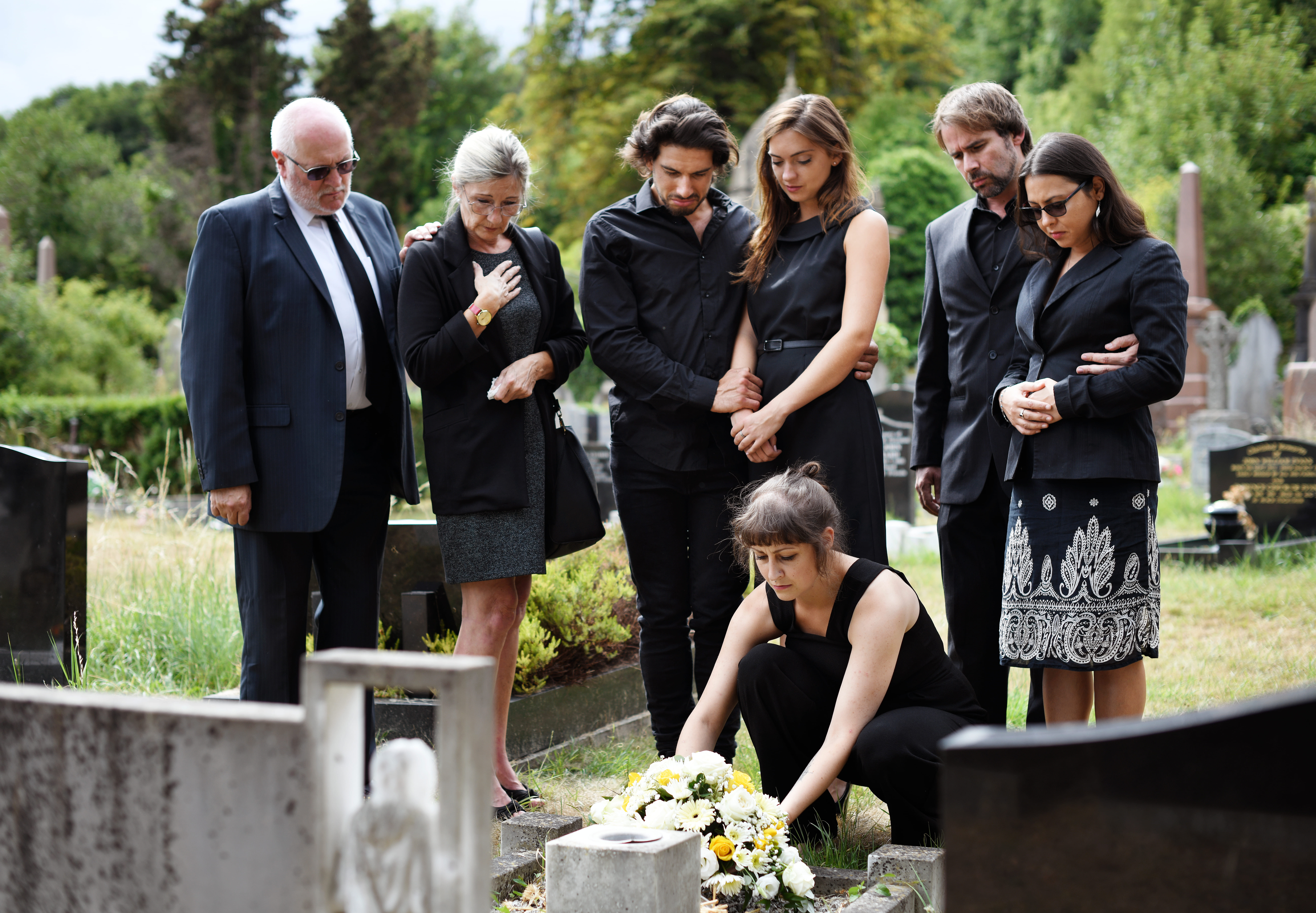 Family laying flowers on the grave in a cemetery | Source: Shutterstock