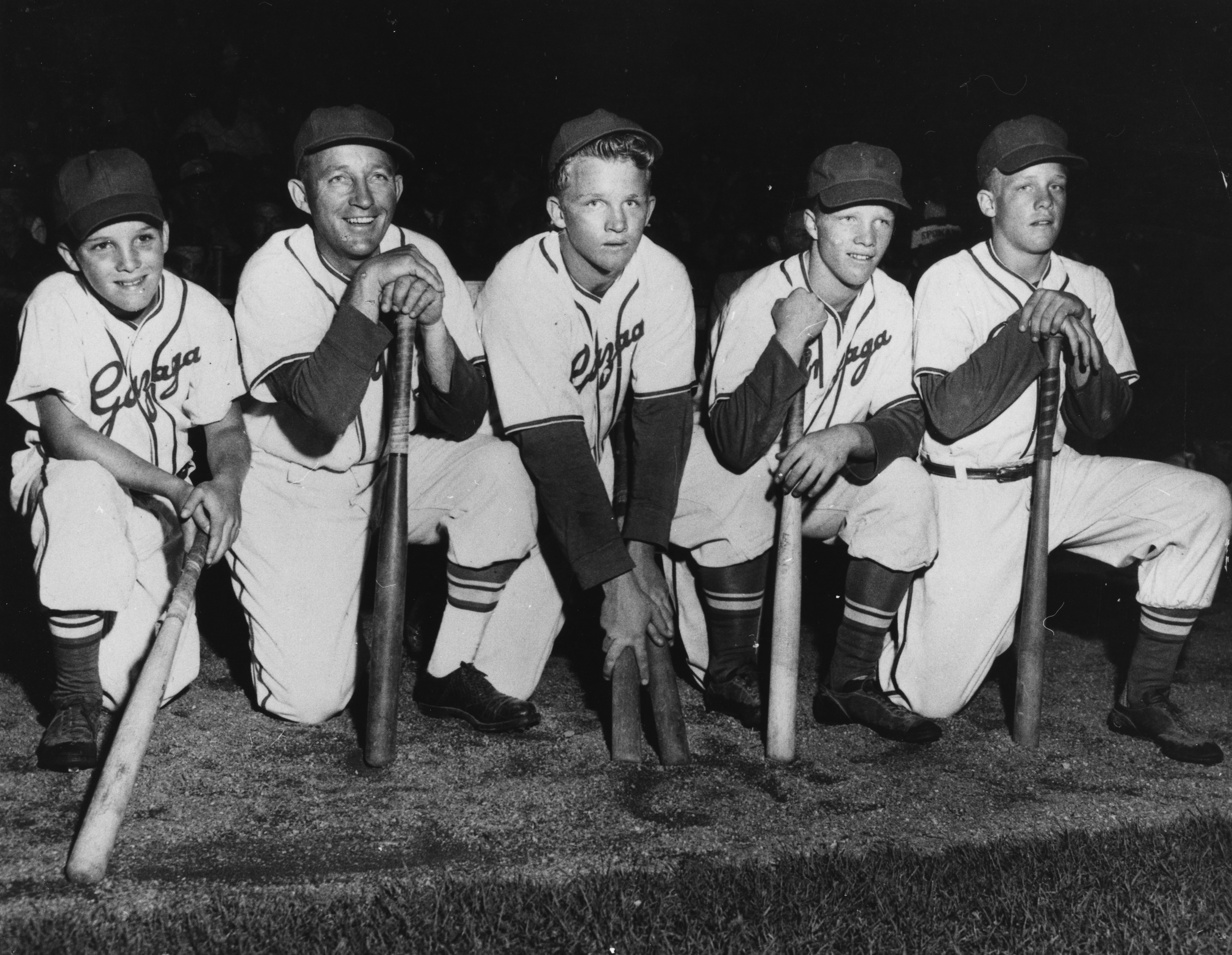 Singer and actor Bing Crosby (second left) and his sons (L-R) Lindsay, Gary, Dennis and Phillip, all wearing baseball uniforms and kneeling with baseball bats, circa 1950. | Source: Getty Images