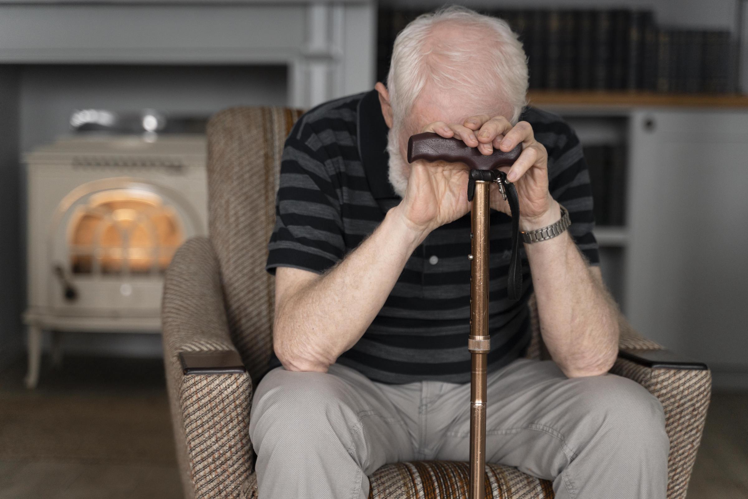 A sad older man leaning on his walking stick | Source: Freepik