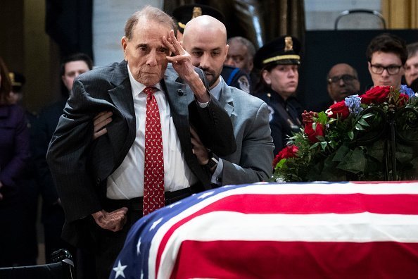 Former Senator Bob Dole stands up and salutes the casket of the late former President George H.W. Bush as he lies in state at the U.S. Capitol, December 4, 2018 in Washington, DC | Photo: Getty Images