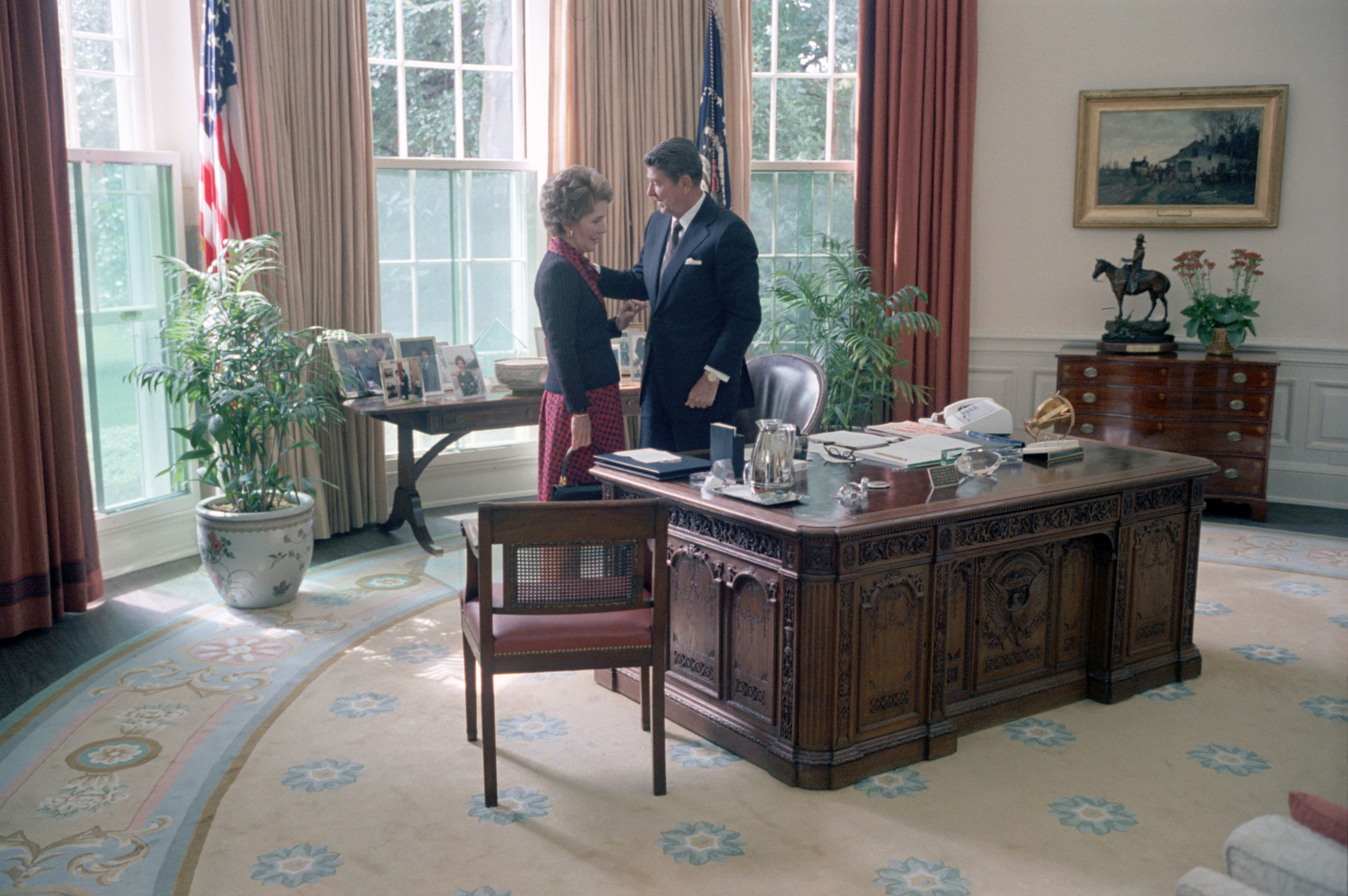 President Ronald Reagan stands with First Lady Nancy Reagan on September 16, 1981, in the Oval Office, decorated with floral rugs, family portraits, and tall windows facing the South Lawn.