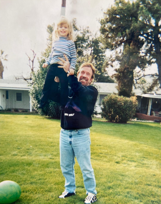 1. Chuck Norris lifts a young Danilee Norris high into the air on a sunlit lawn, both smiling—an easy, playful moment frozen in time. | Source: Instagram/d.ani.lee