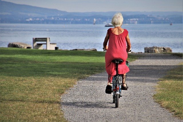 An elderly woman taking a ride on a bicycle by the sea. | Photo: Getty Images.