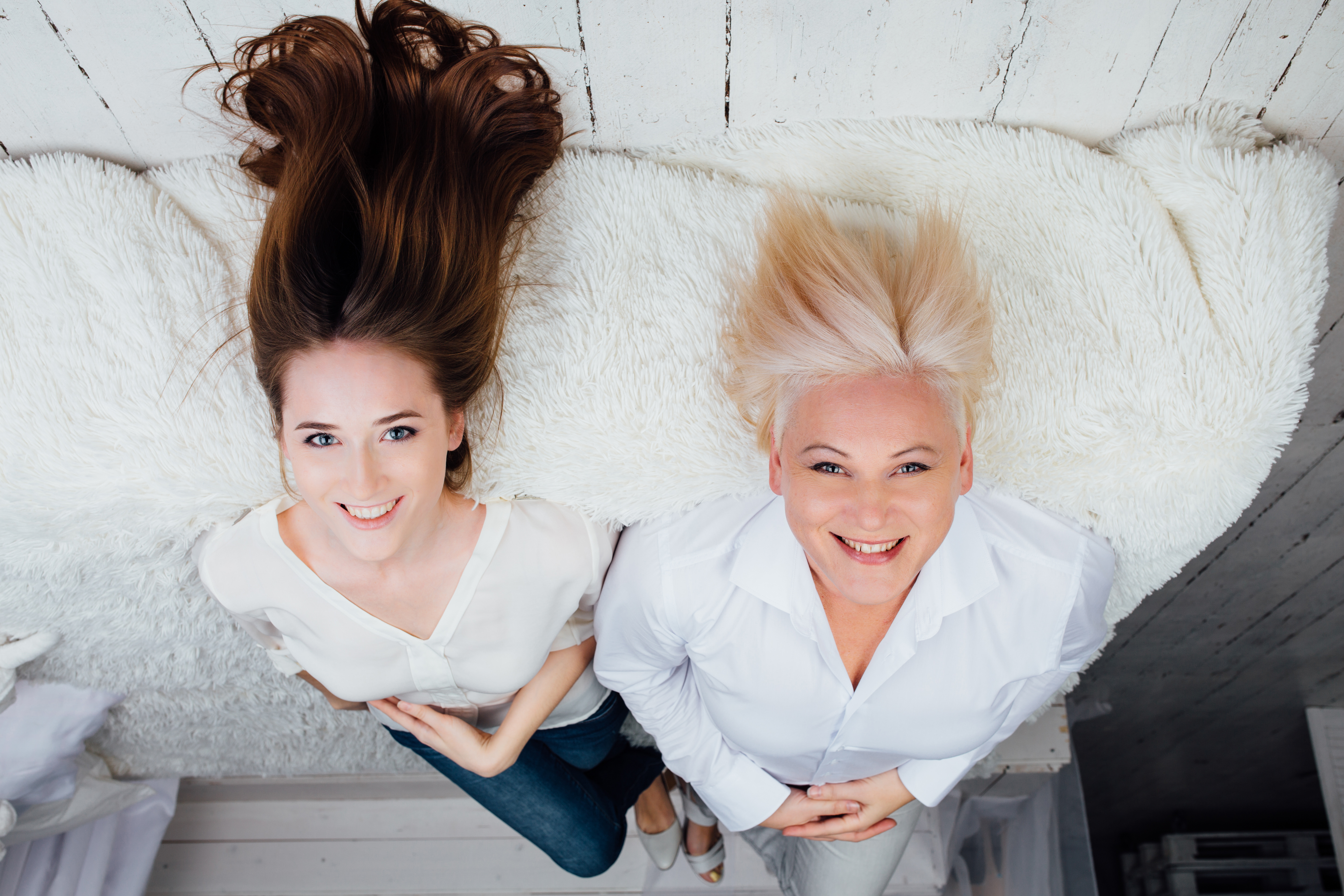 Mother and daughter lying on bed while smiling at the camera | Source: Shutterstock