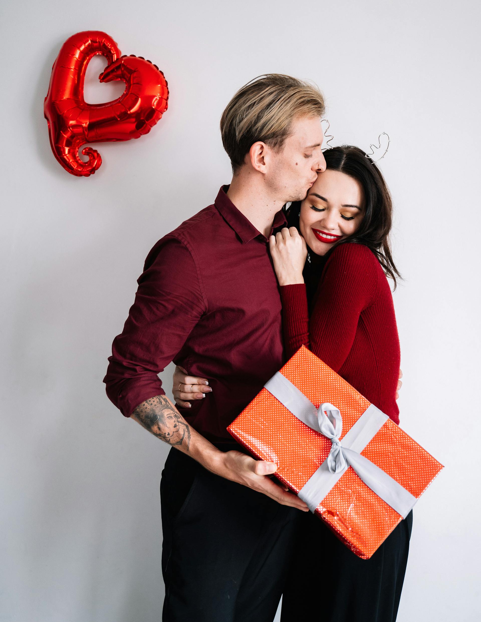 A husband kissing his wife while holding a gift | Source: Pexels