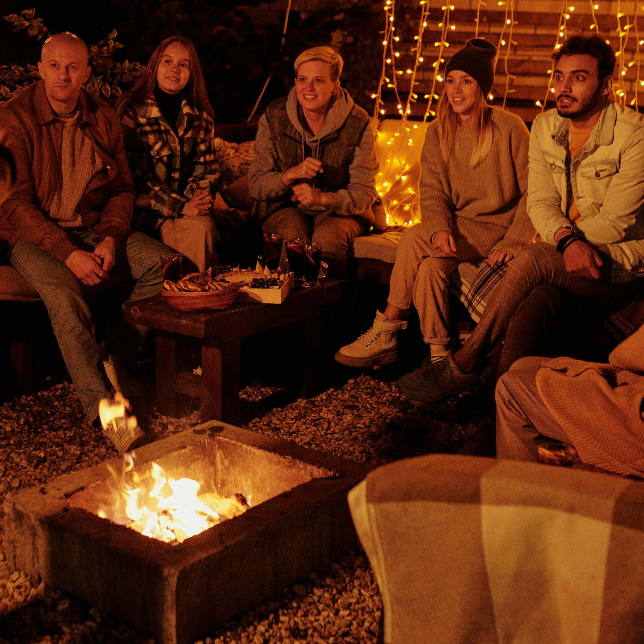 A celebratory group gathered around a fire, focused on someone offscreen | Source: Pexels