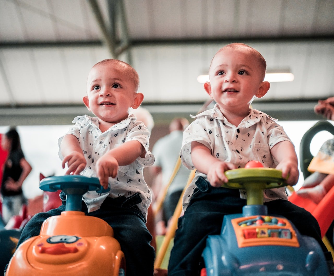 Twin babies sitting on toy cars | Source: Pexels