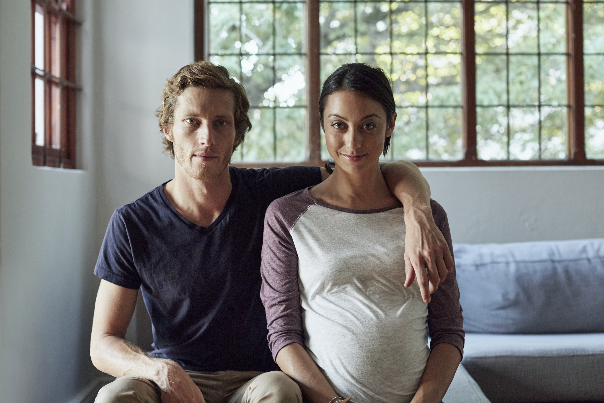 Portrait of expectant mid adult couple sitting on sofa at home | Photo: Getty Images