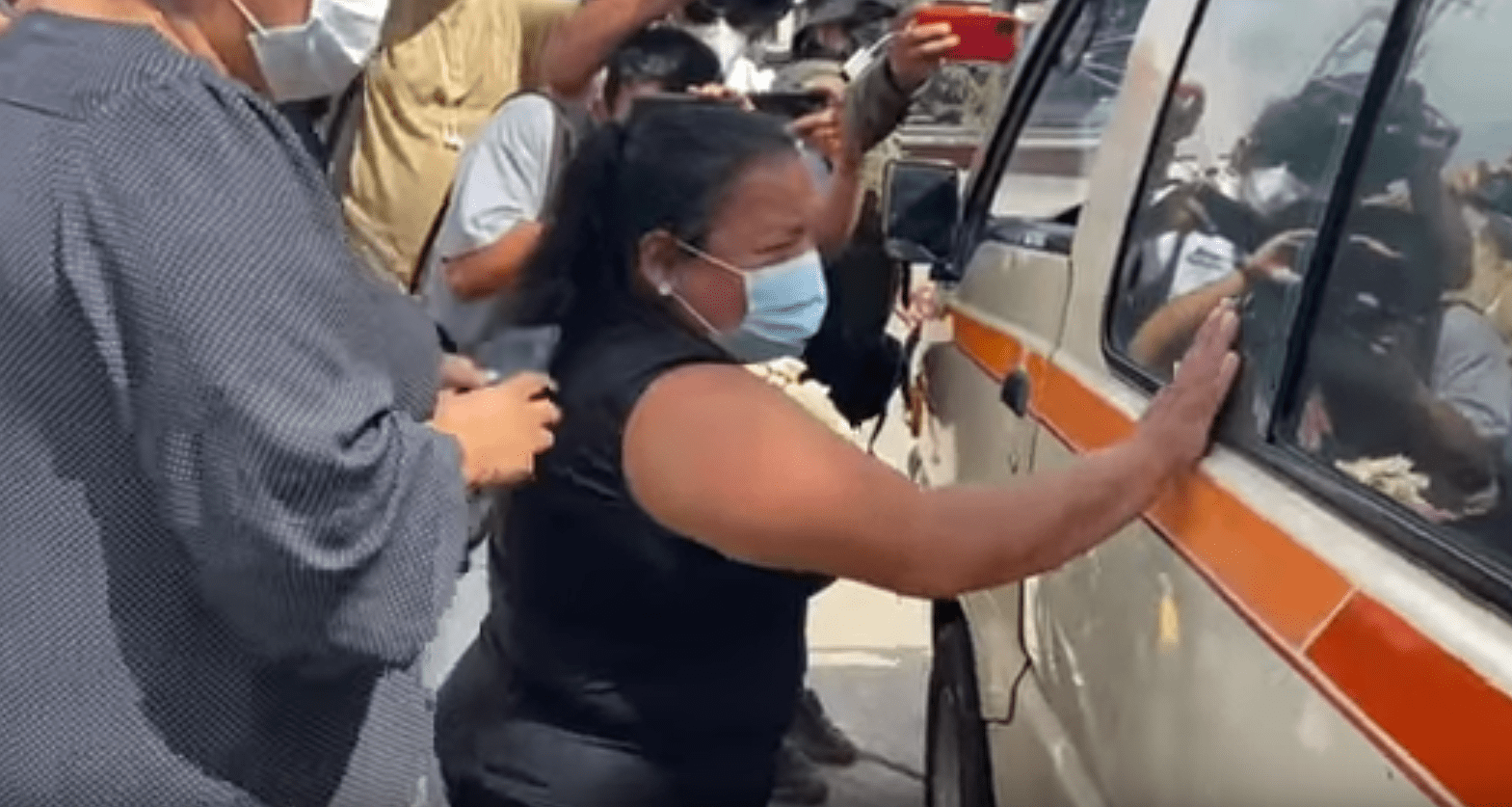 Mujer afligida llorando junto al vehículo que lleva el ataúd de su fallecido esposo. | Foto: YouTube/Guatevisión 