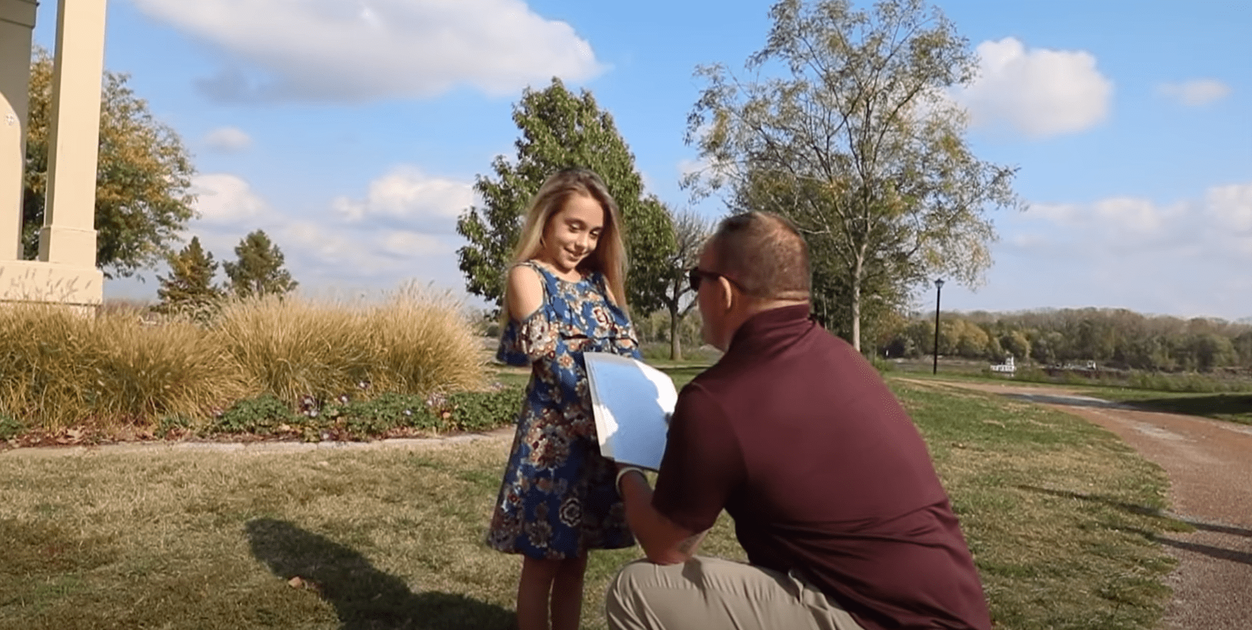 Tim kneels in front of Kylee during their family photoshoot to read a letter. | Source: youtube.com/Tim Bobbitt