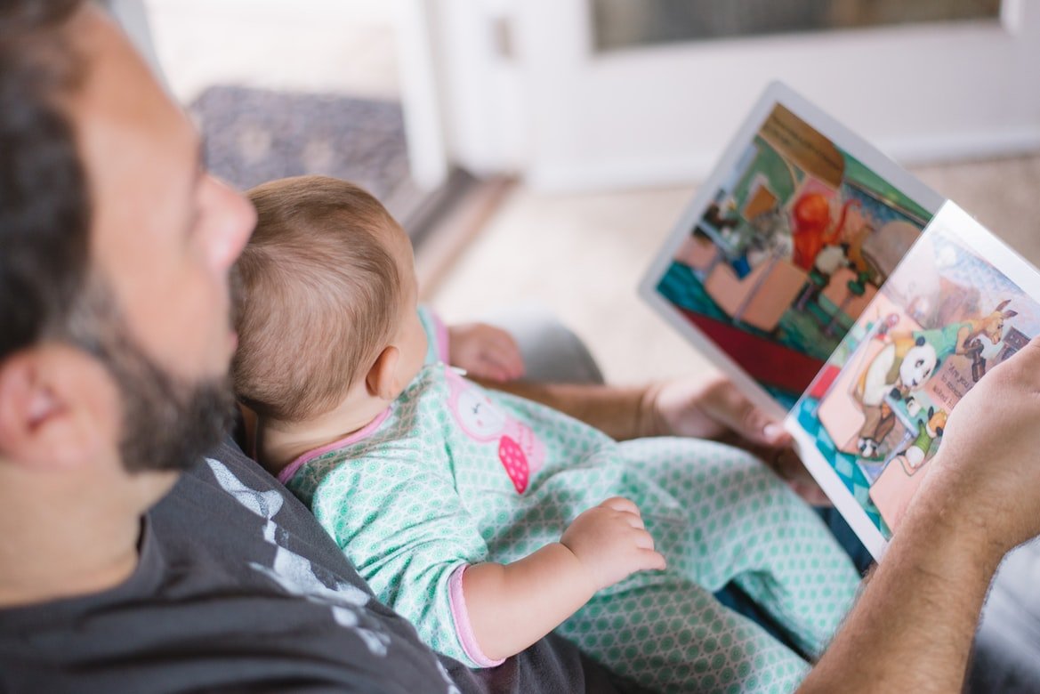 Hombre le lee un cuento a su bebé. | Foto: Unsplash